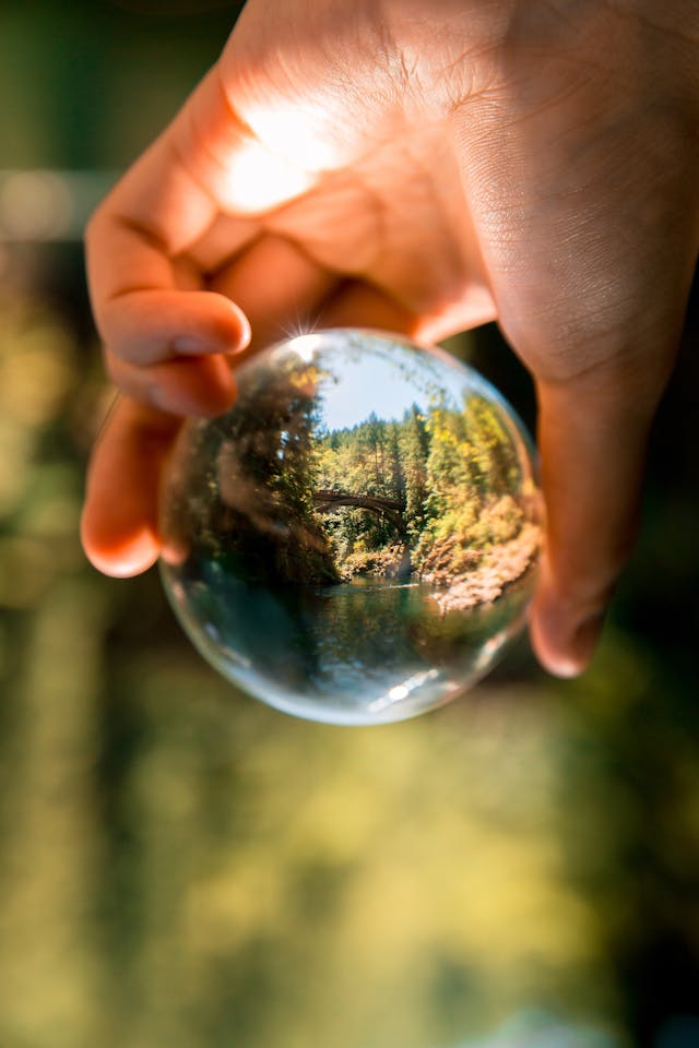 An illustrative photo of a person holding a clear glass ball, capturing the reflection of the surrounding environment 