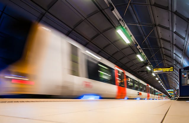 An illustrative photo of a beige and red train speeding along the tracks