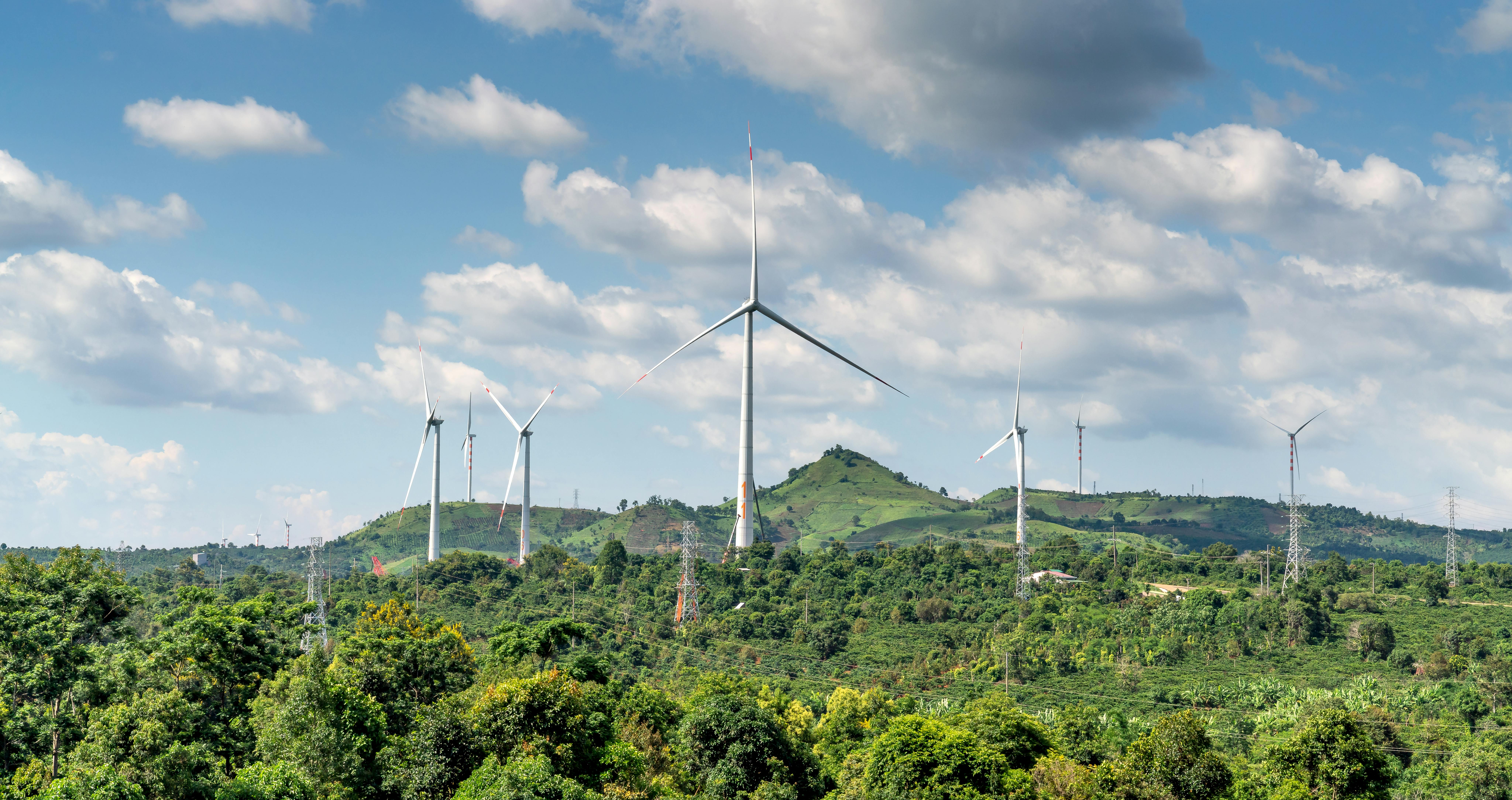 Photo by Pexels An illustrative photo of a wind turbine on a green grass field under white clouds.