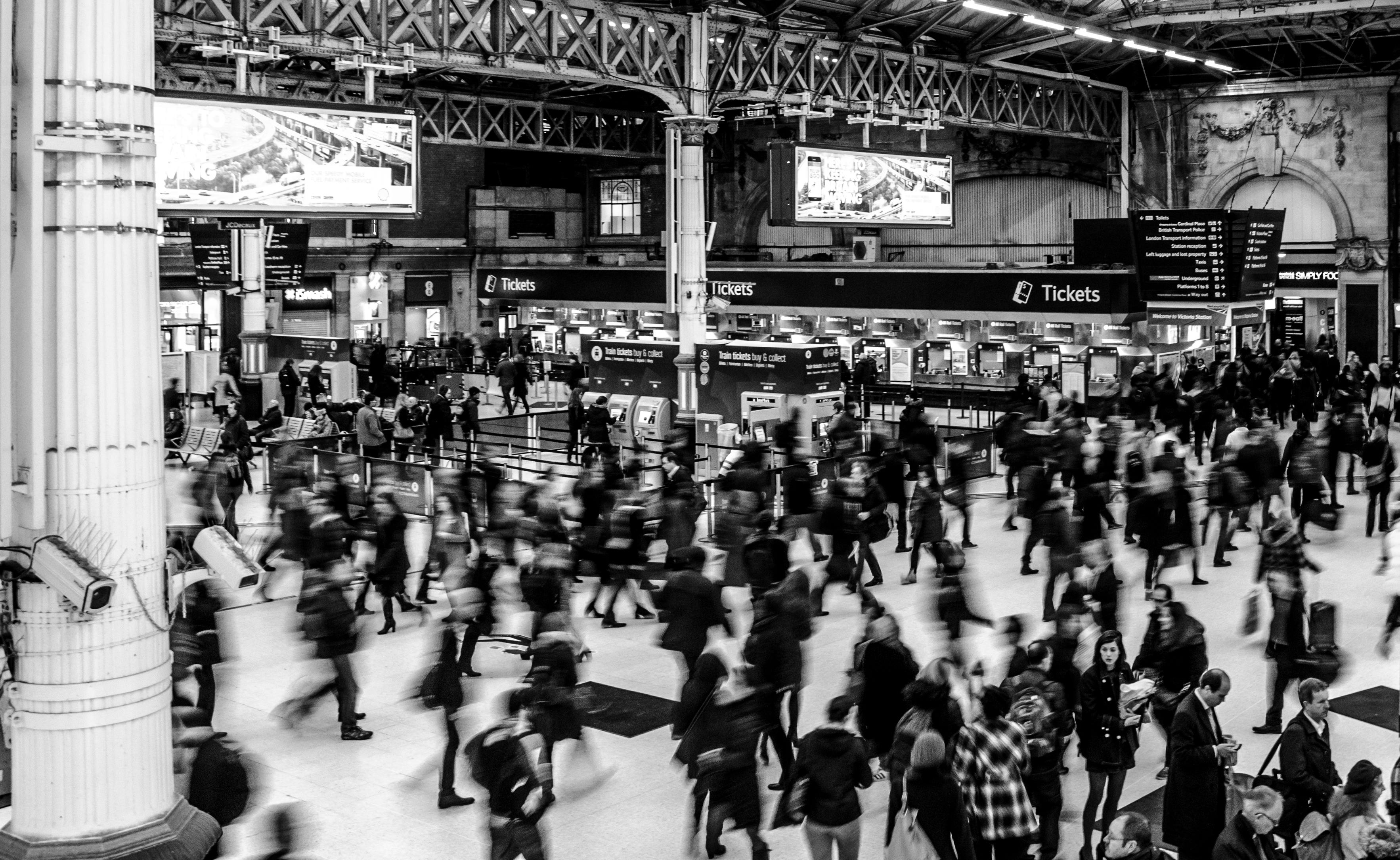 Photo by Pexels An illustrative photo of people walking through a train station in grayscale