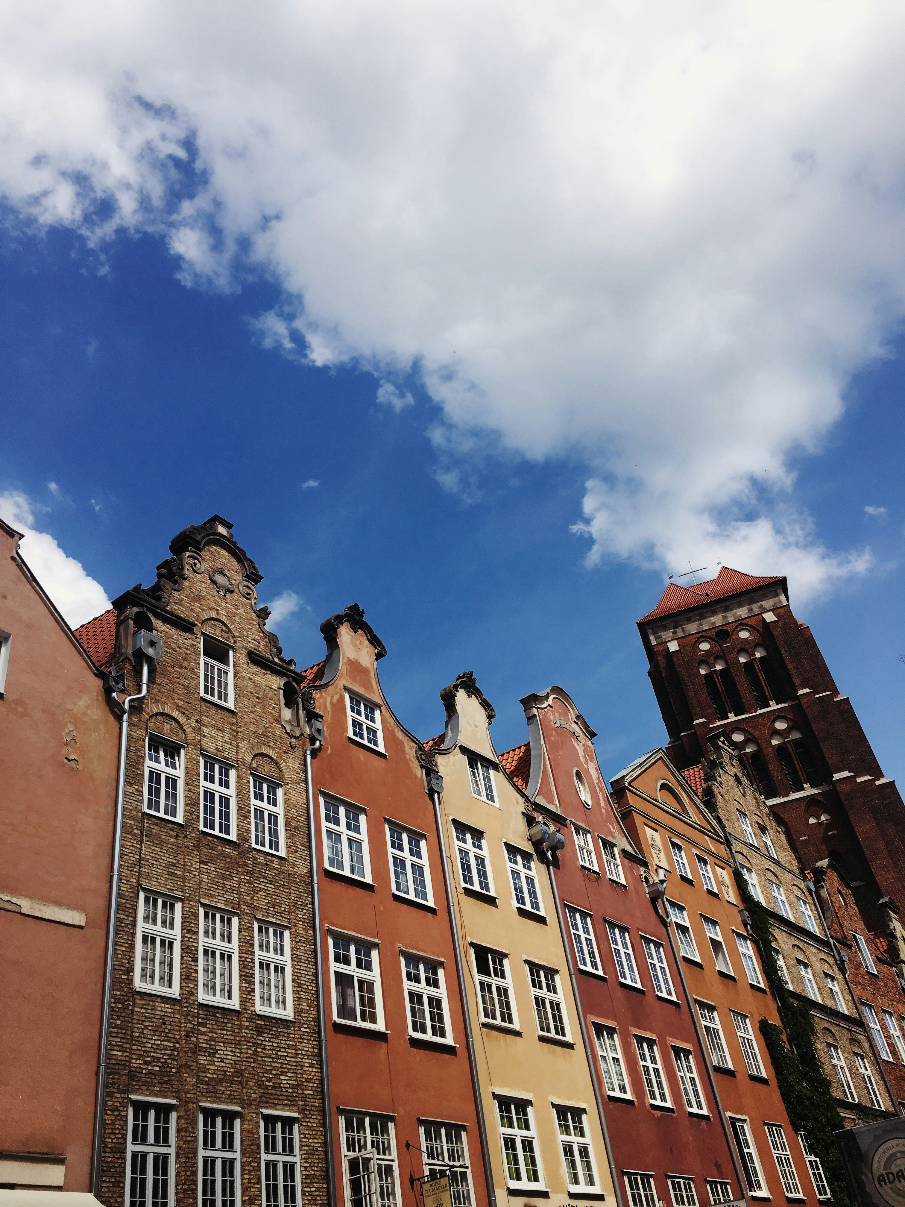 An illustrative photo of brown concrete buildings in Gdansk under blue sky during daytime