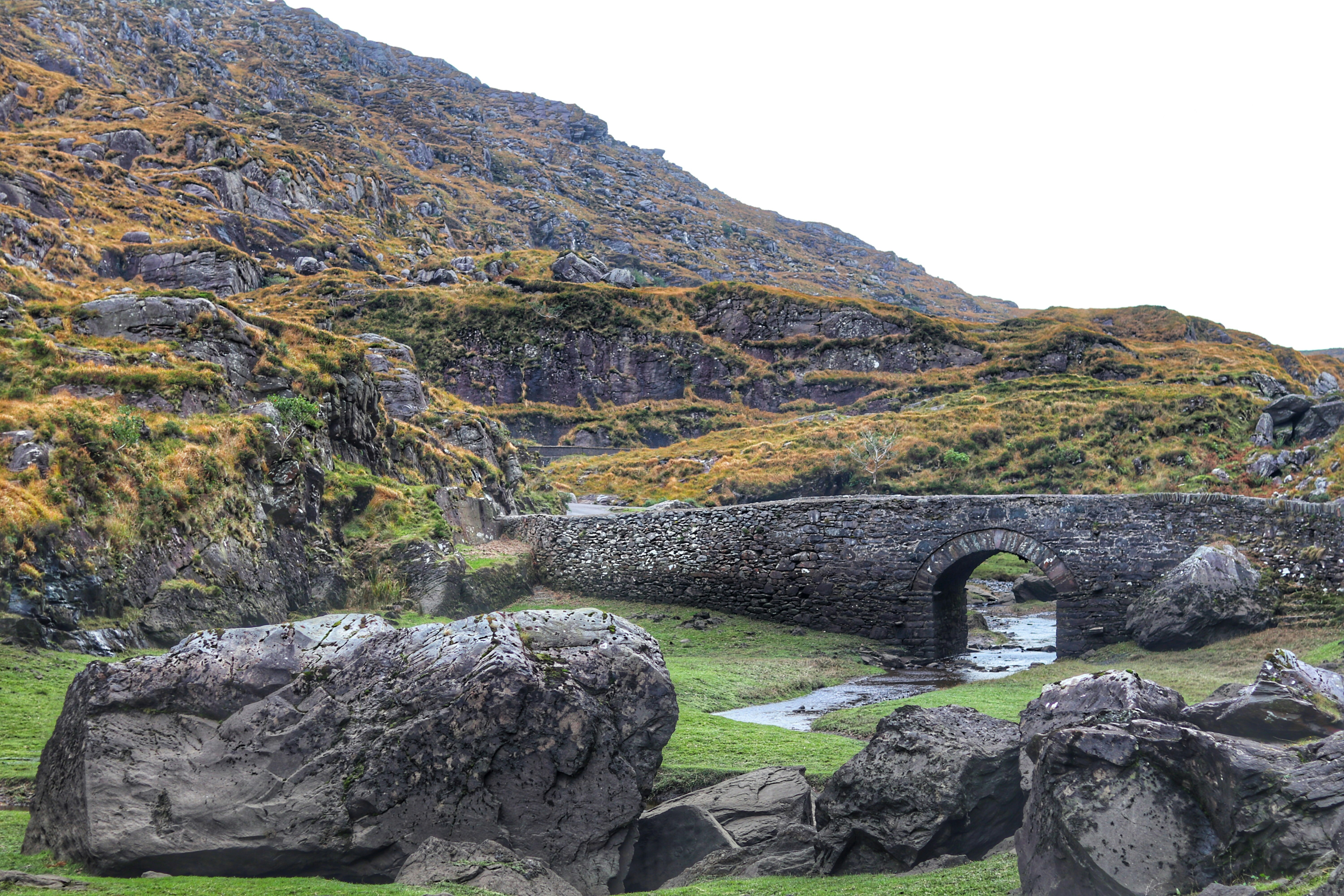 An illustrative photo of a gray concrete bridge beside a mountain