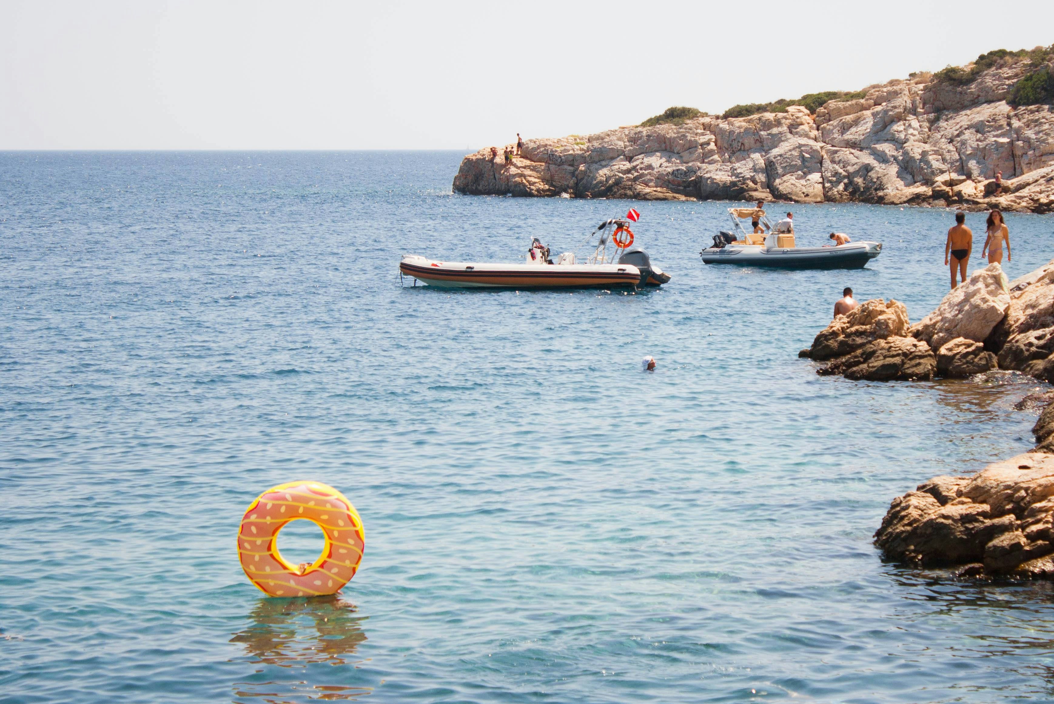 An illustrative photo of a group of people swimming in the sea near a rocky shore