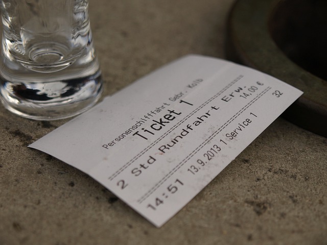 An illustrative photo of a ticket, glass, and paper receipt on a surface