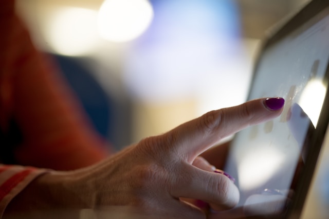 An illustrative photo of a person pointing at a tablet, focusing intently on the screen