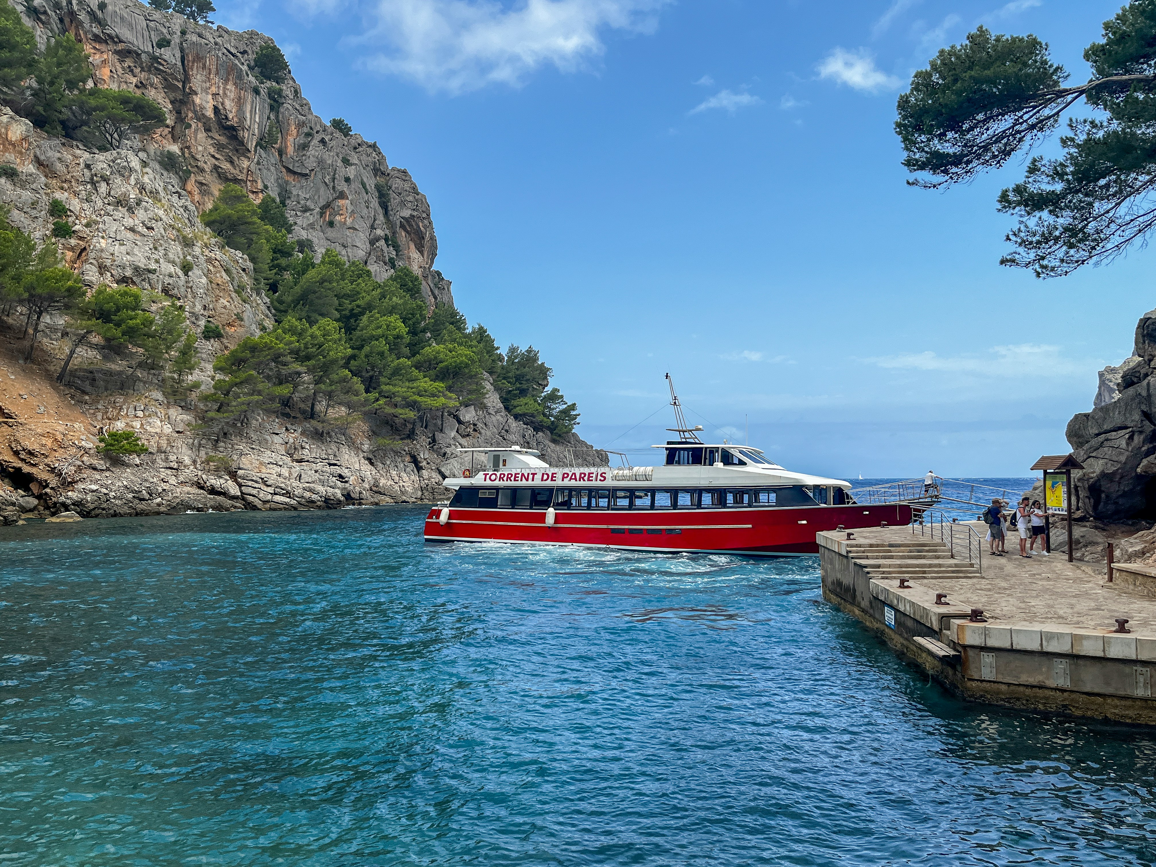 An illustrative photo of a red and white boat in a body of water near rocky mountain