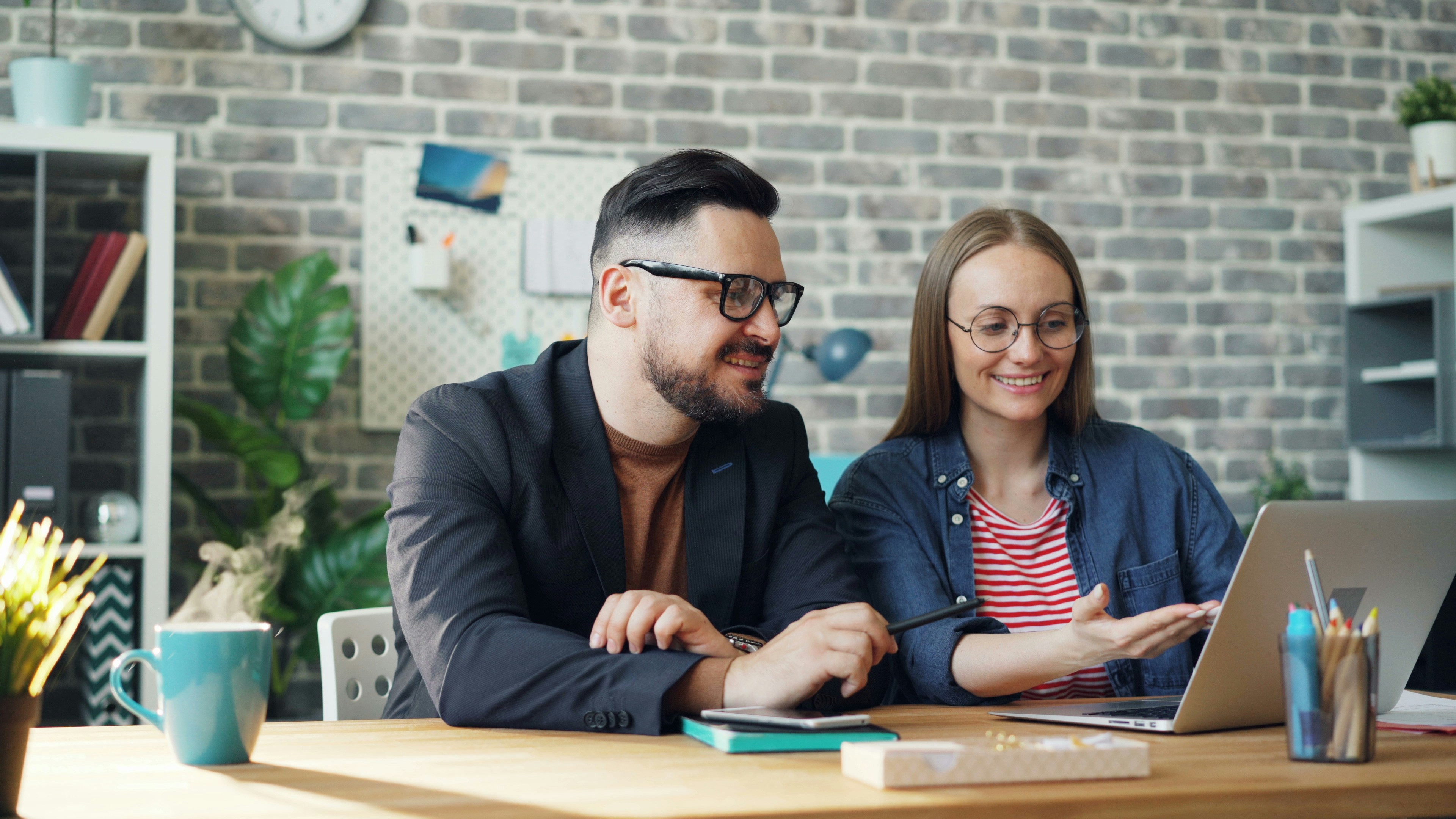 Photo by Unsplash An illustrative photo of a man and a woman sitting at a table looking at a laptop