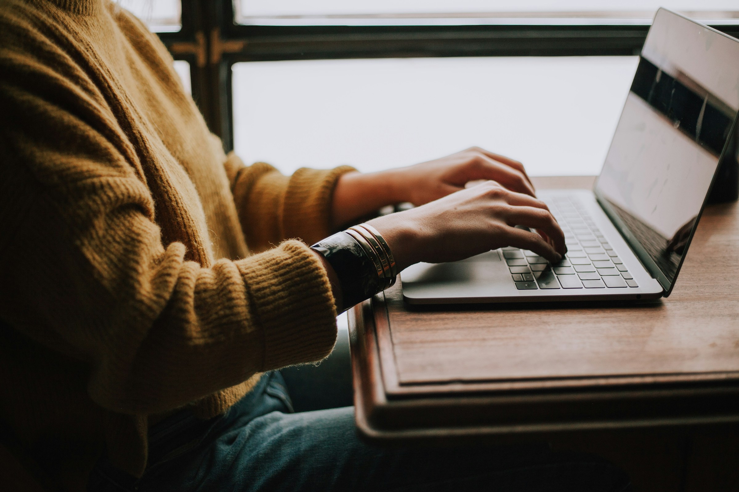 An illustrative photo of a person sitting in front of laptop.