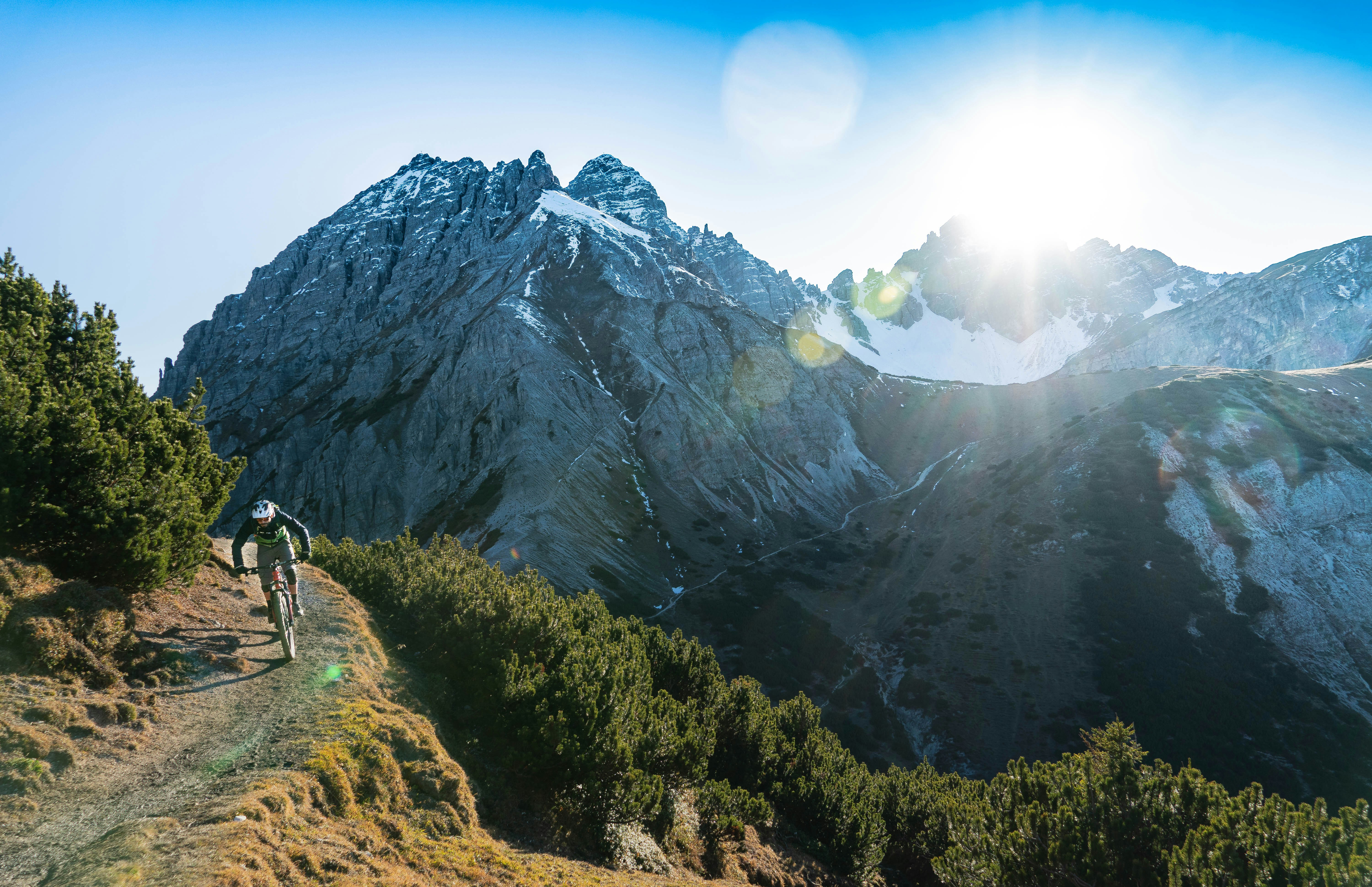 An illustrative photo of a person riding a bike on a trail in front of a mountain