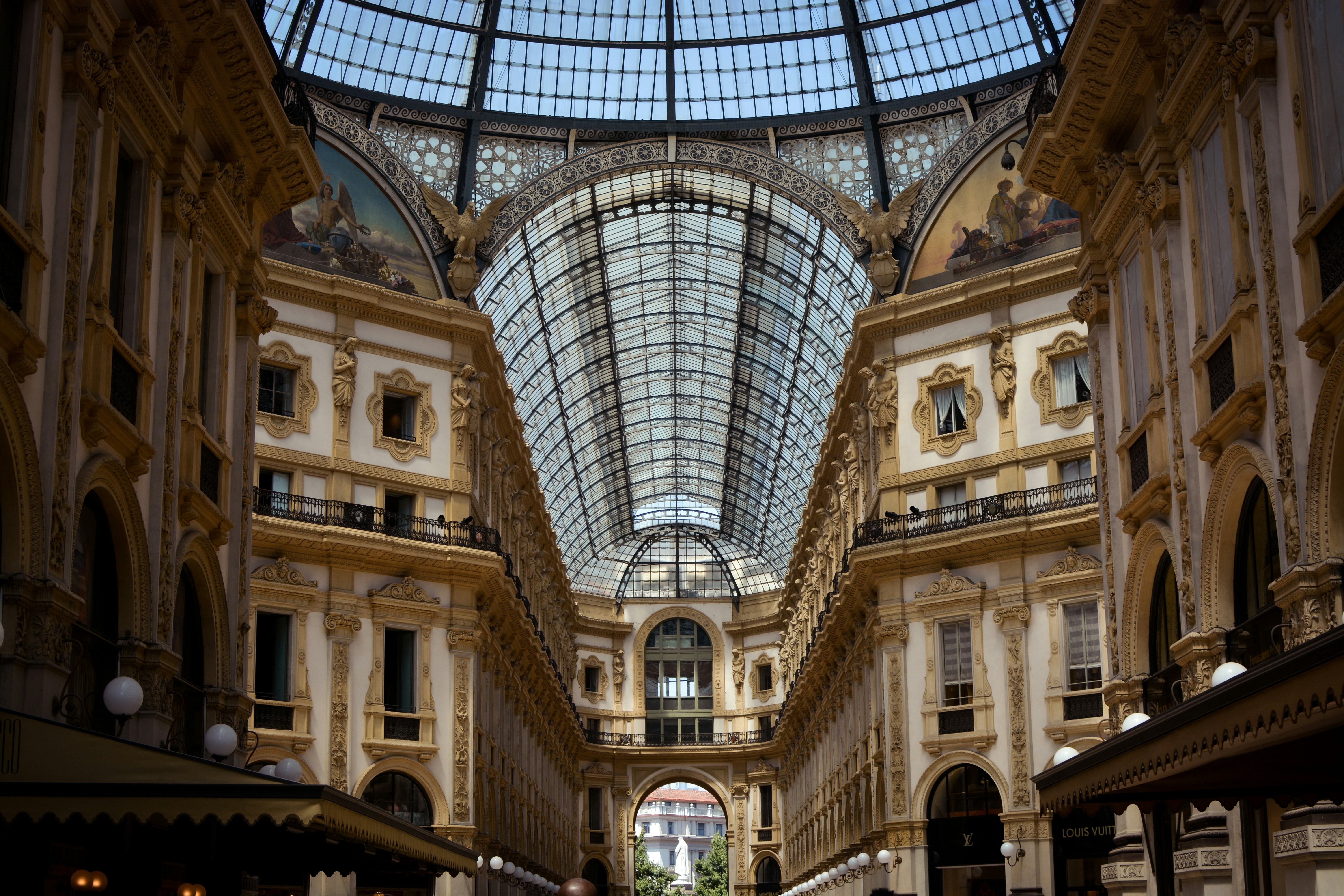 An illustrative photo of a beige concrete building with glass ceilings in Milan