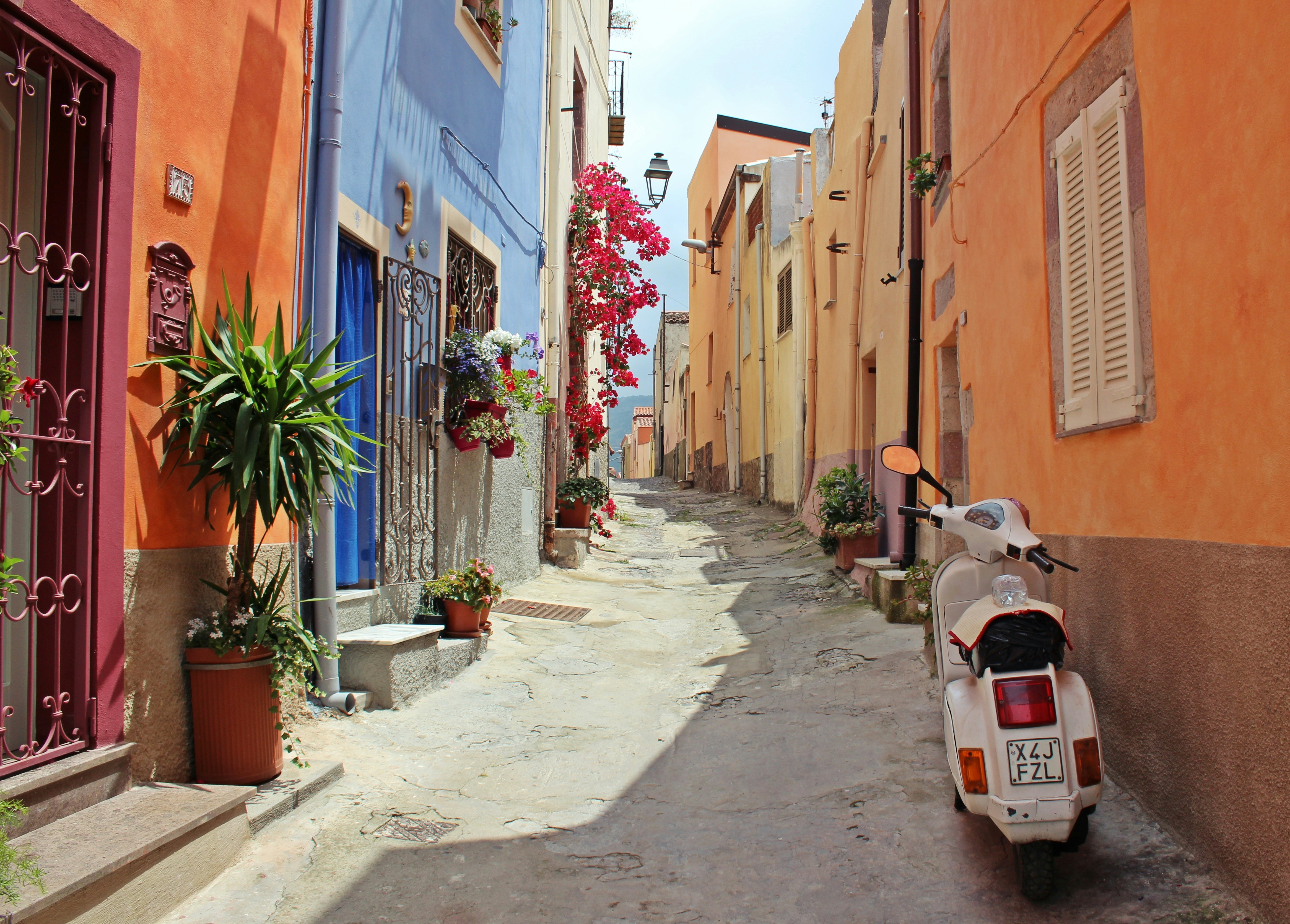 An illustrative photo of a white scooter near a building on a narrow street