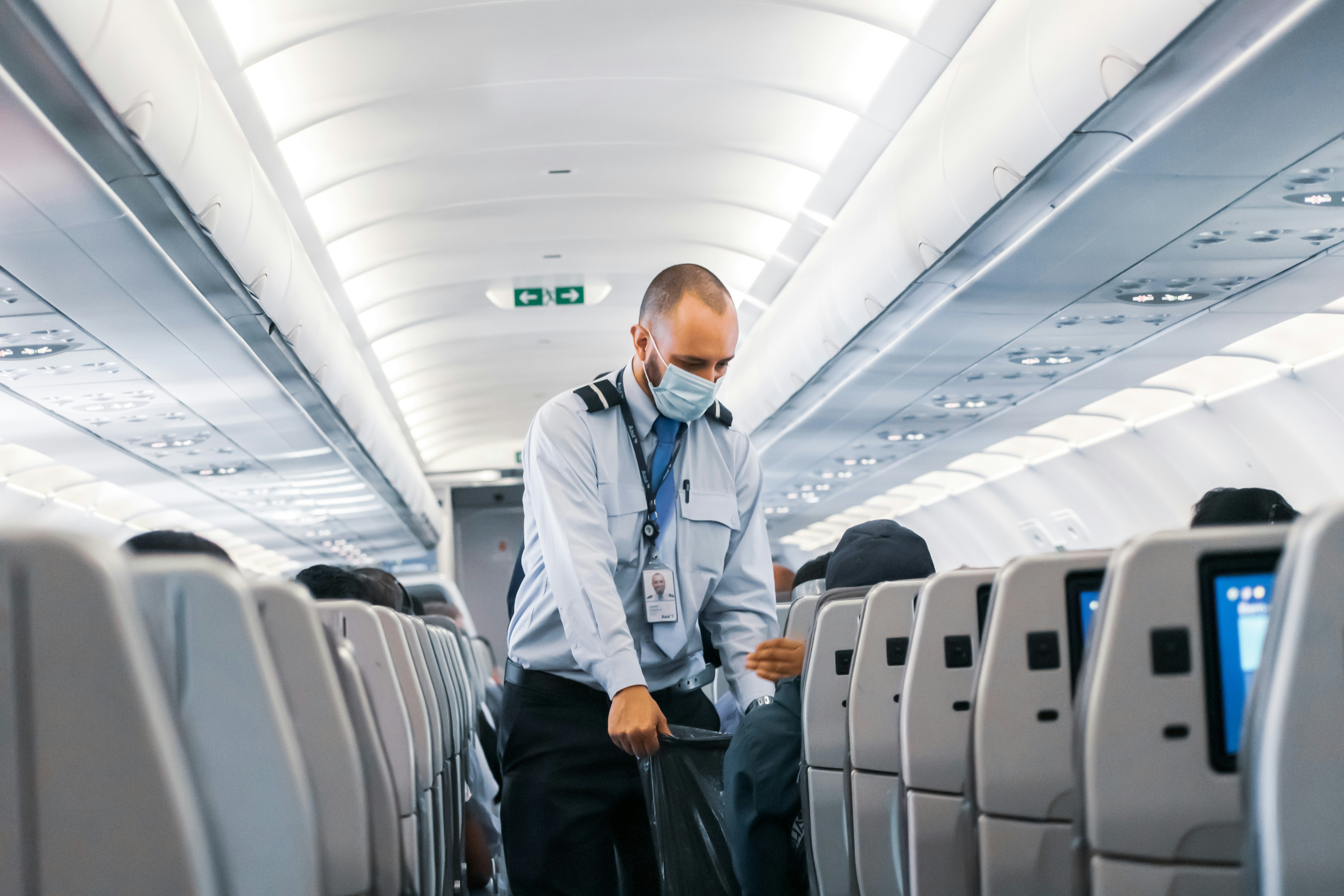 An illustrative photo of a steward in a mask standing in the plane