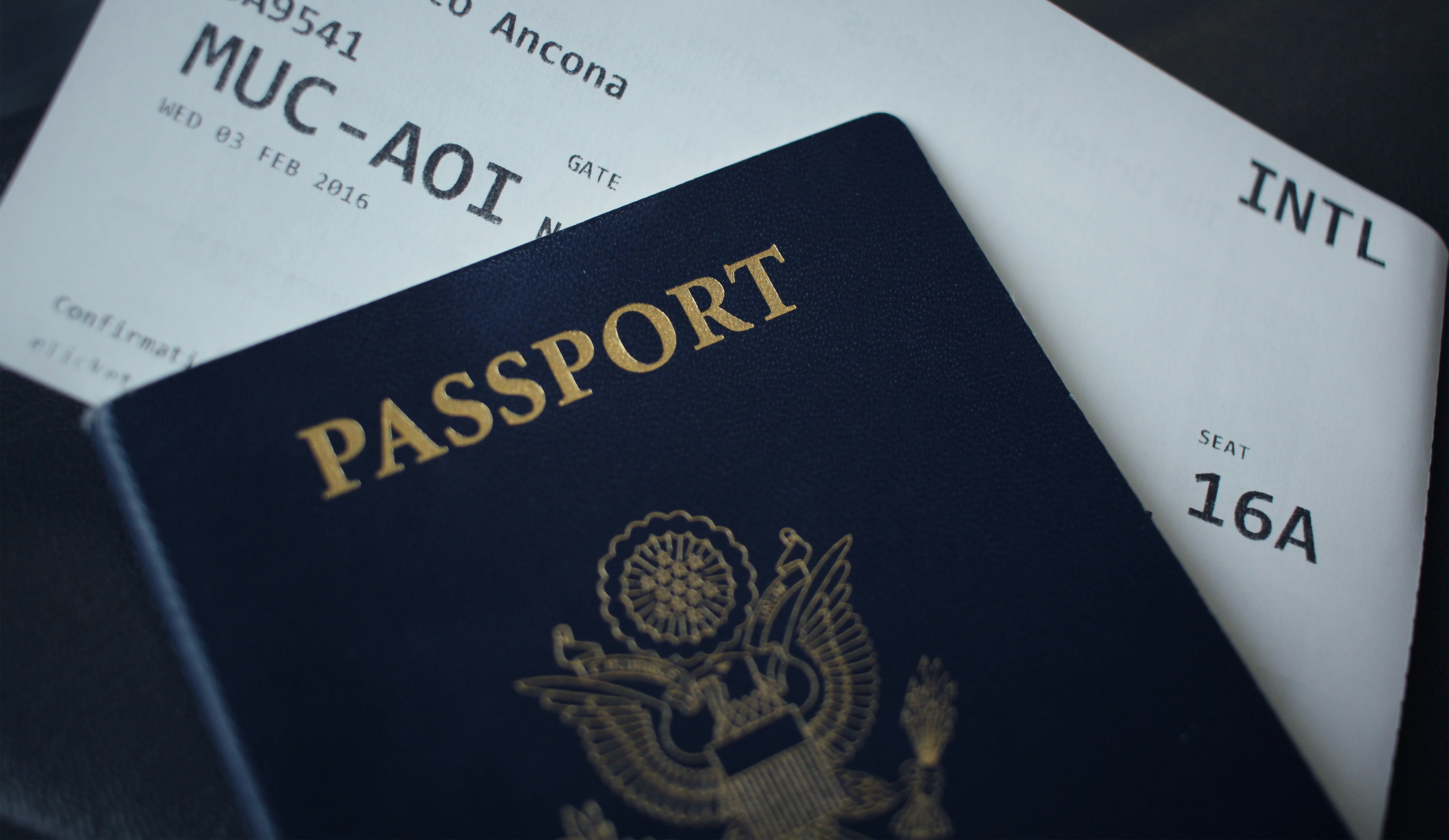 An illustrative photo of a passport on top of an airplane boarding pass