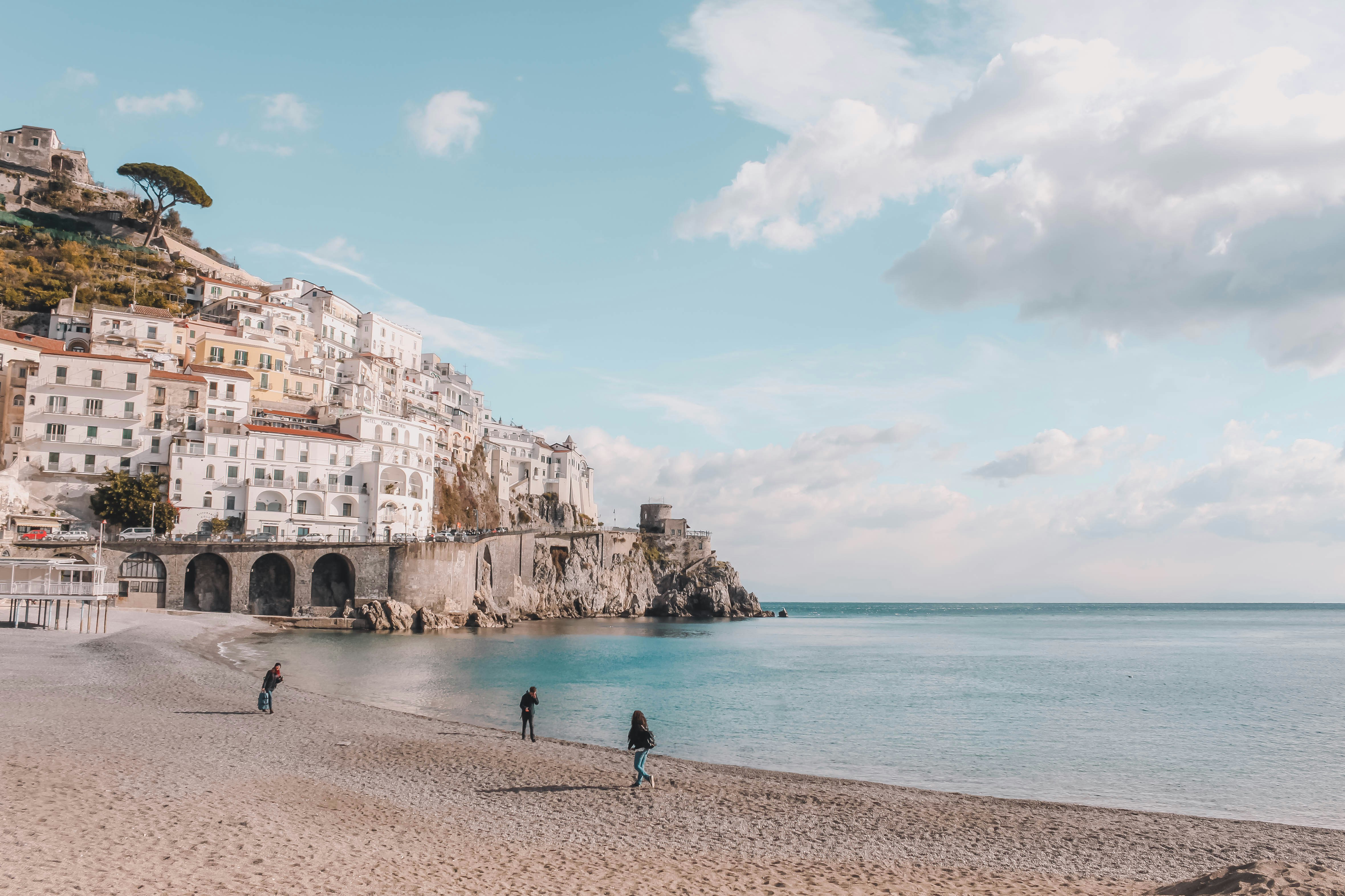 An illustrative photo of people walking on a beach next to the ocean.