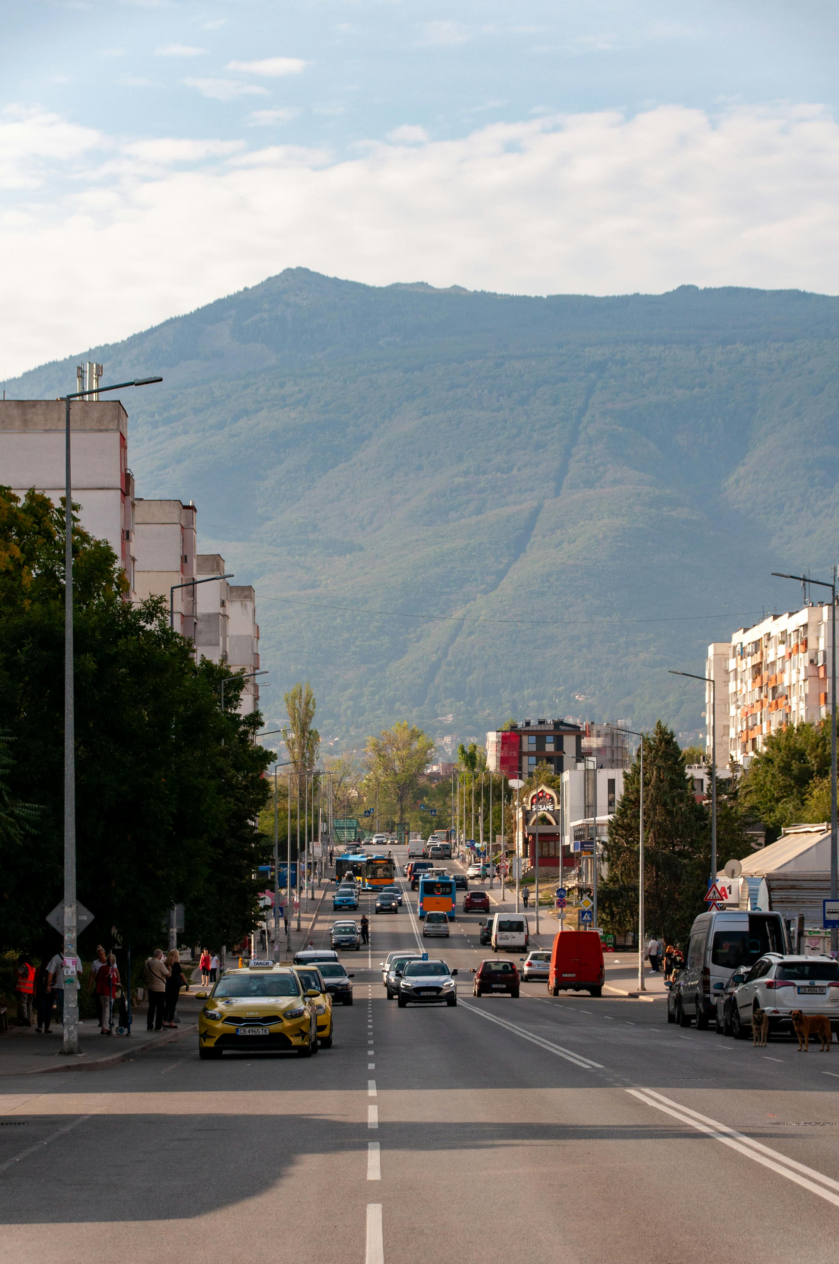 An illustrative photo of a road with many cars with mountains in the background