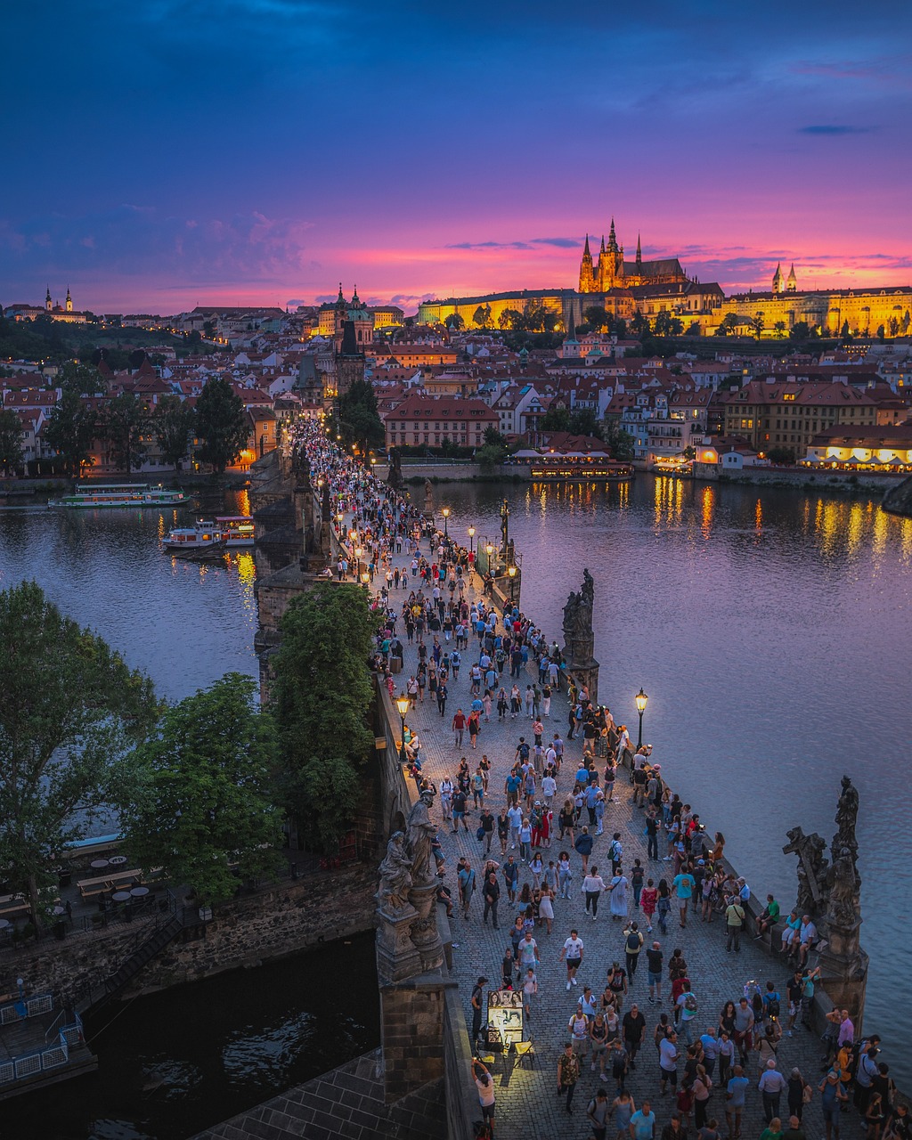 An illustrative photo of people walking on the bridge in Prague during nighttime