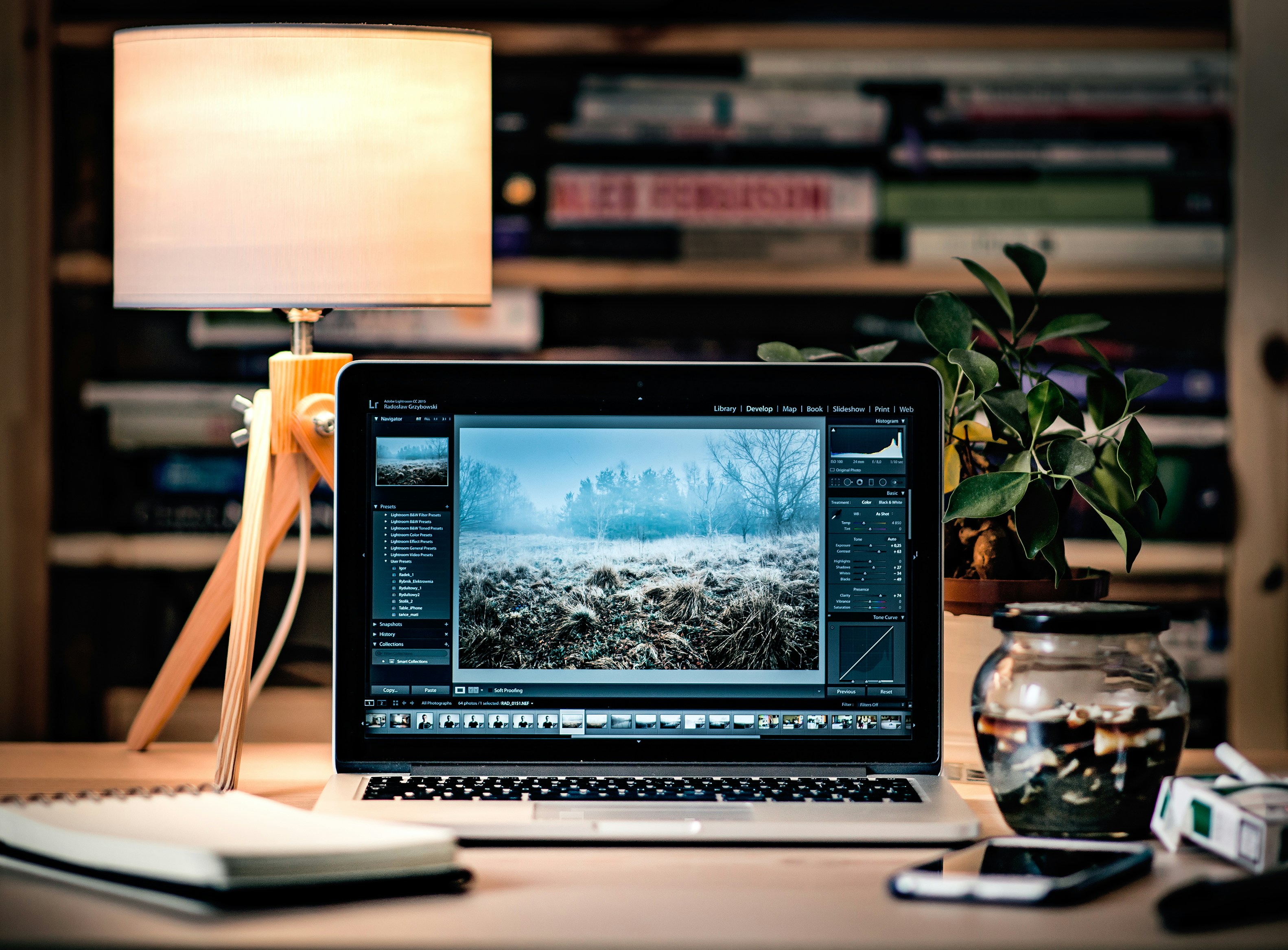 An illustrative photo of a laptop on a wooden table beside a lamp