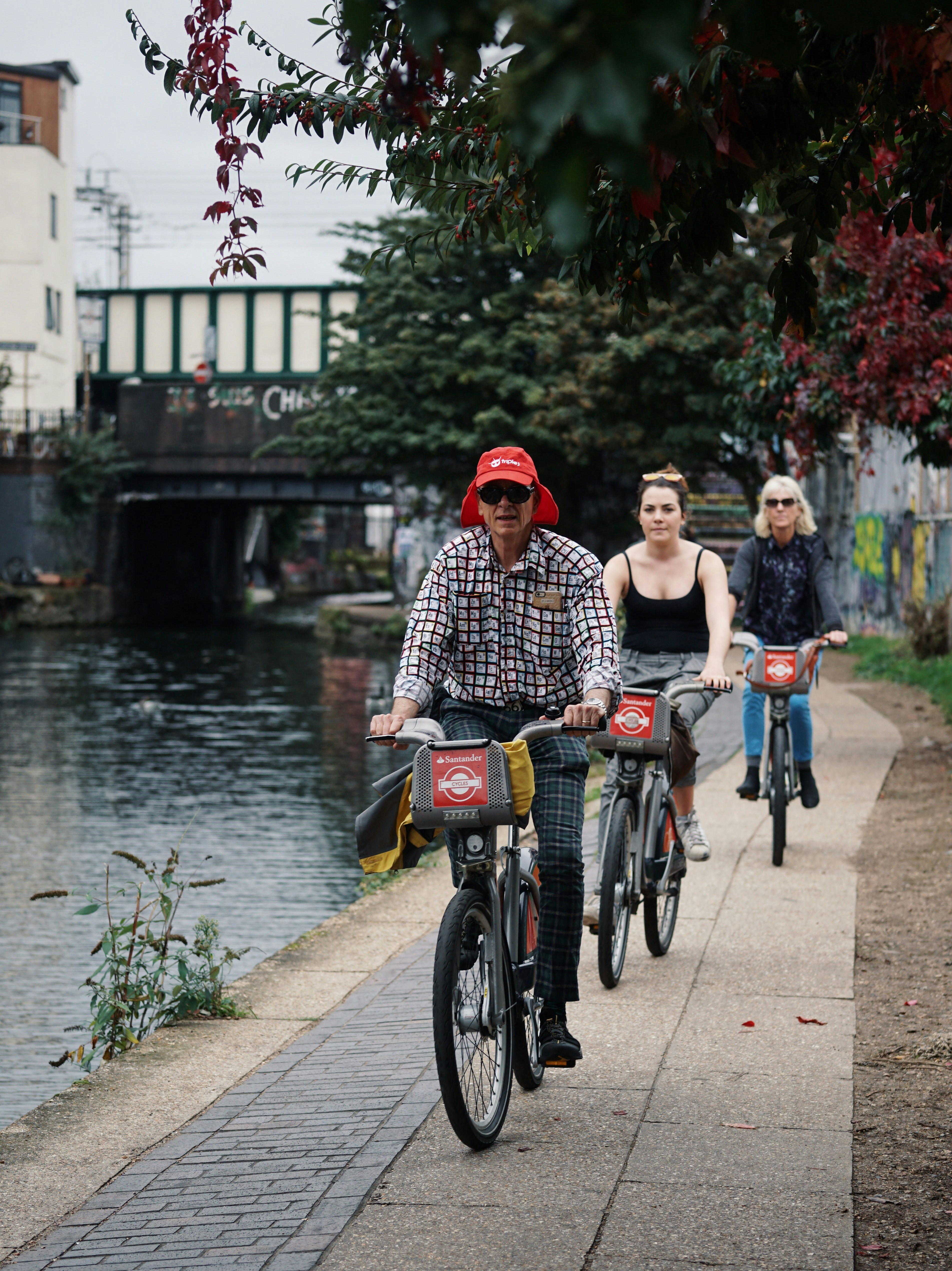 An illustrative photo of three people riding bicycles near a body of water in the city