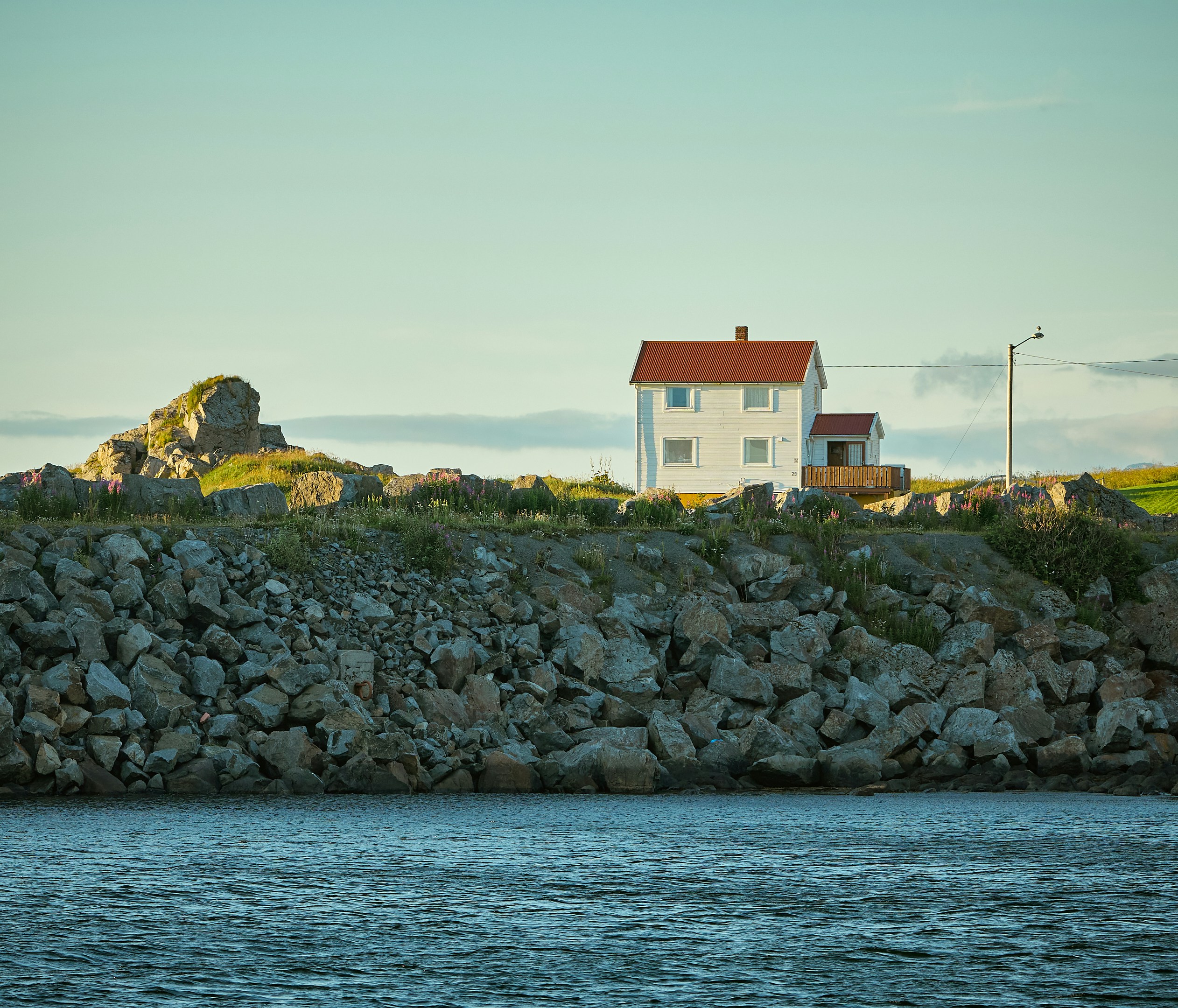 An illustrative photo of a house on a rocky hill by the water.