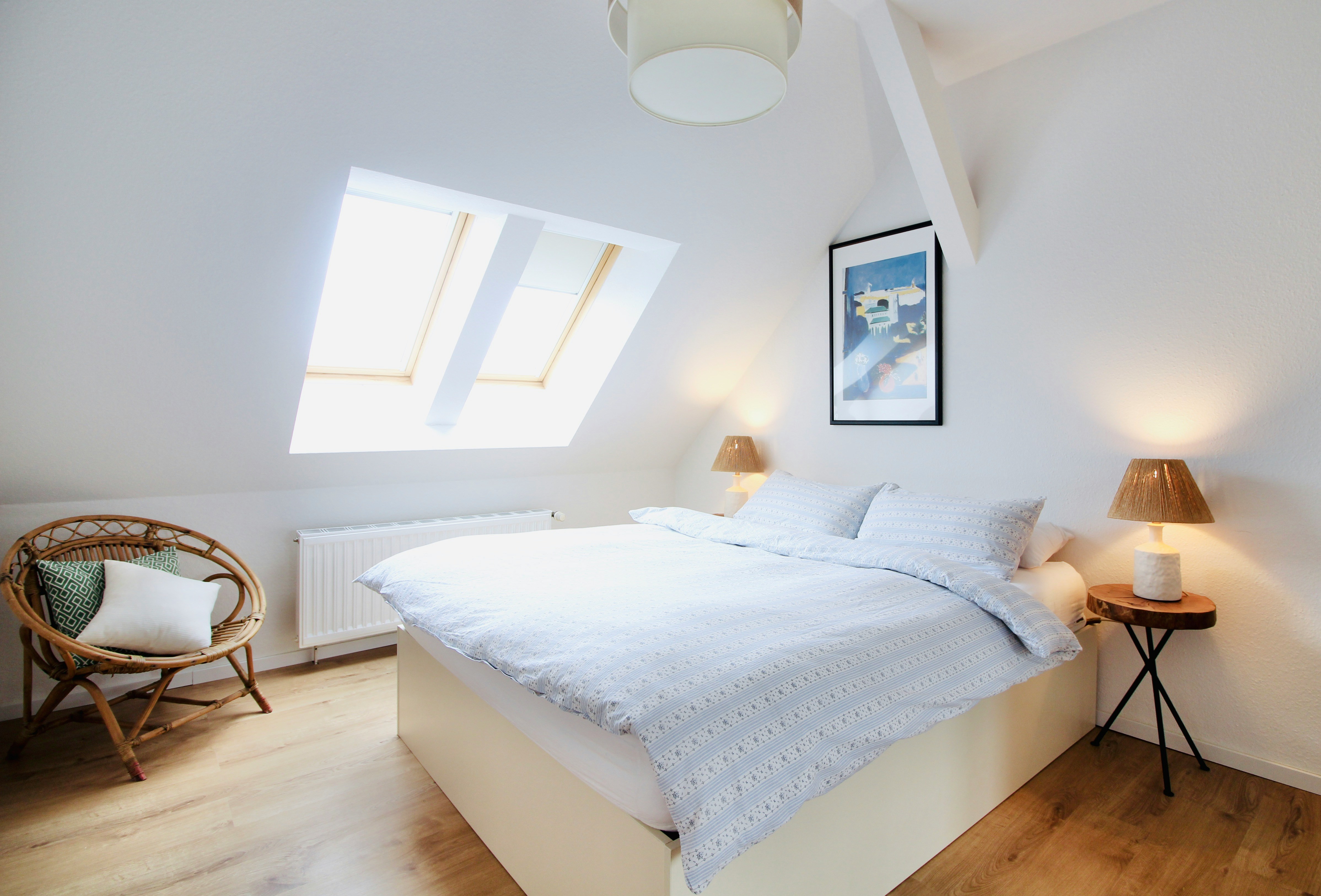 An illustrative photo of a light bedroom with a white bed in it