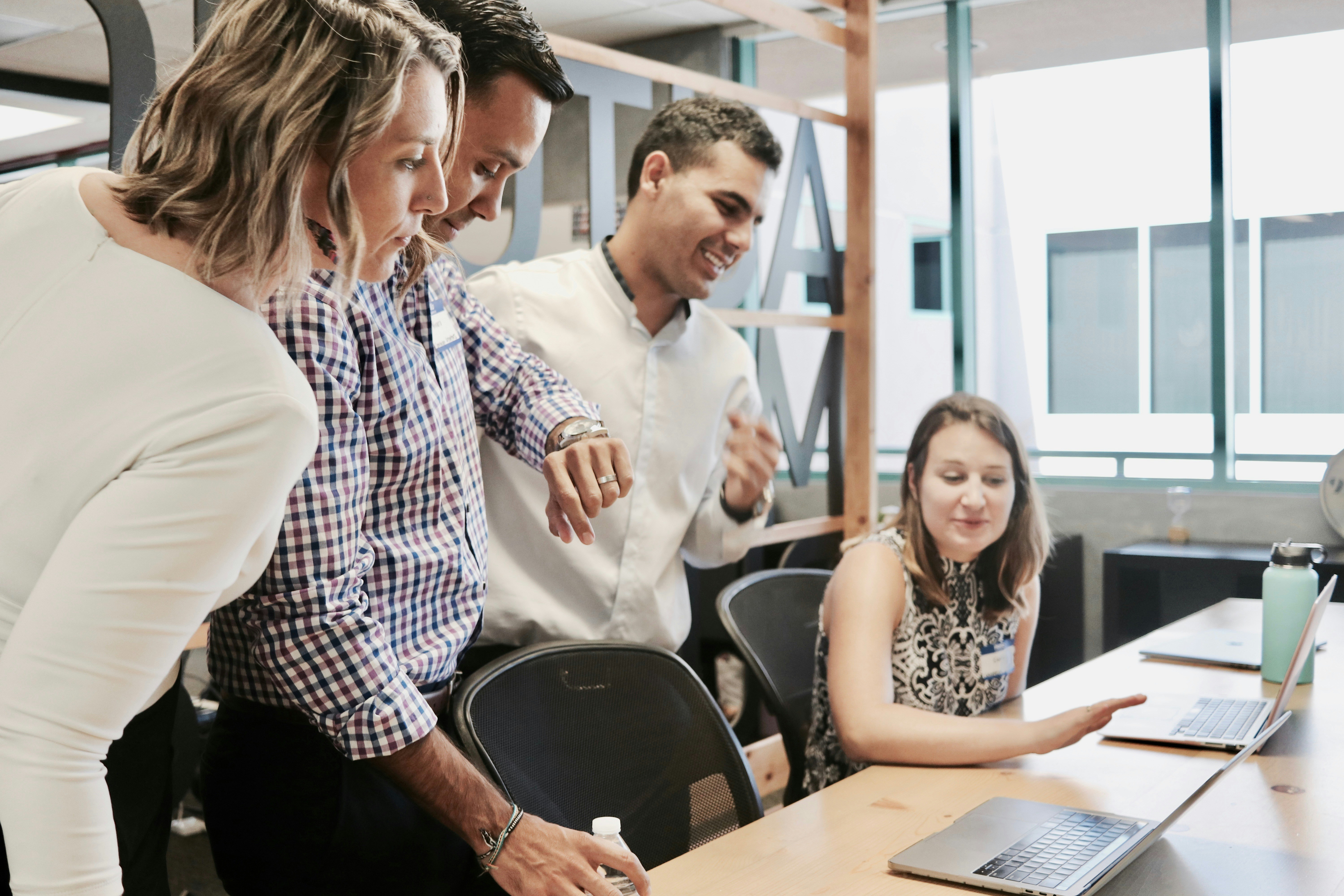 An illustrative photo of people standing near the table with laptops on it 