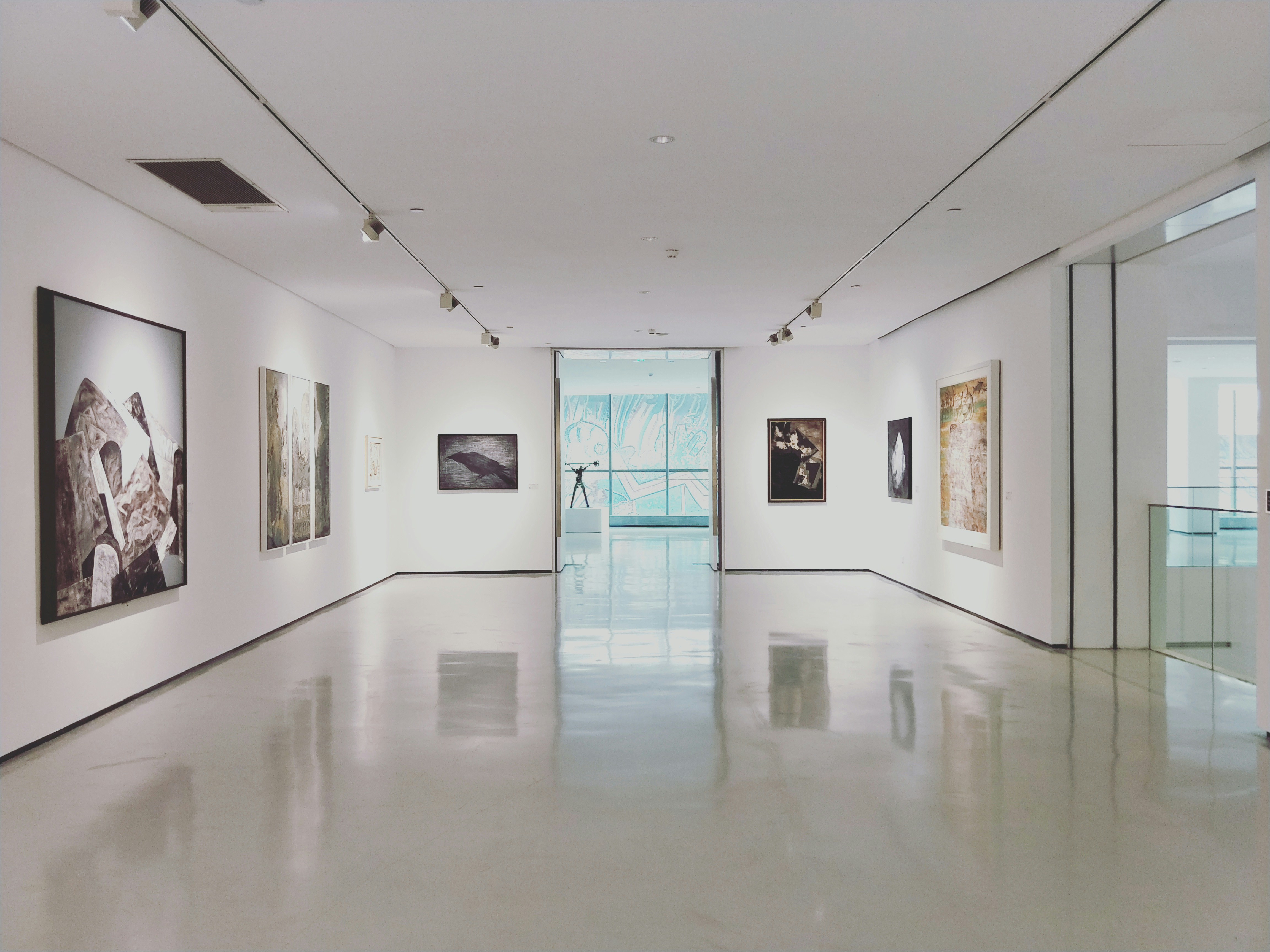 An illustrative photo of a gallery with modern paintings on white walls