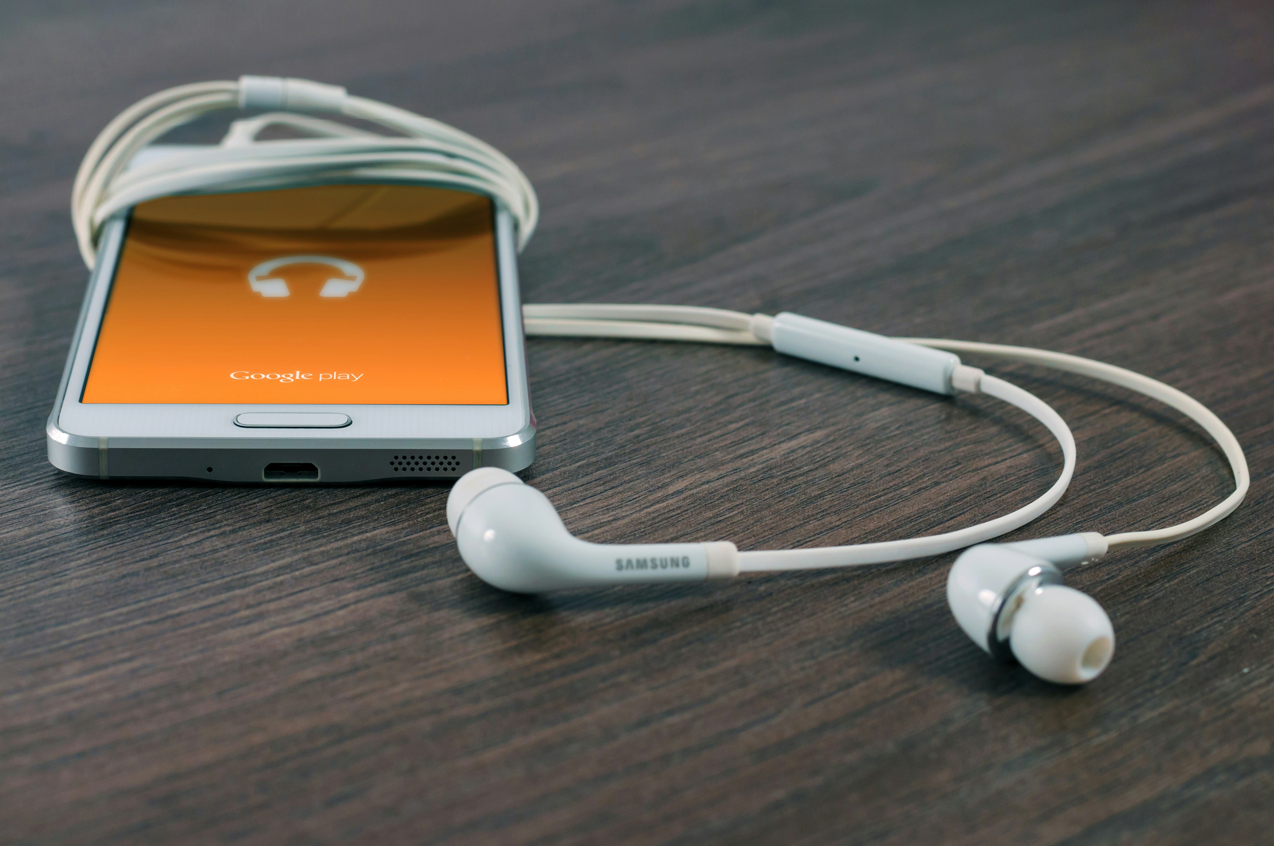 An illustrative photo of white smartphone turned beside white earbuds on table