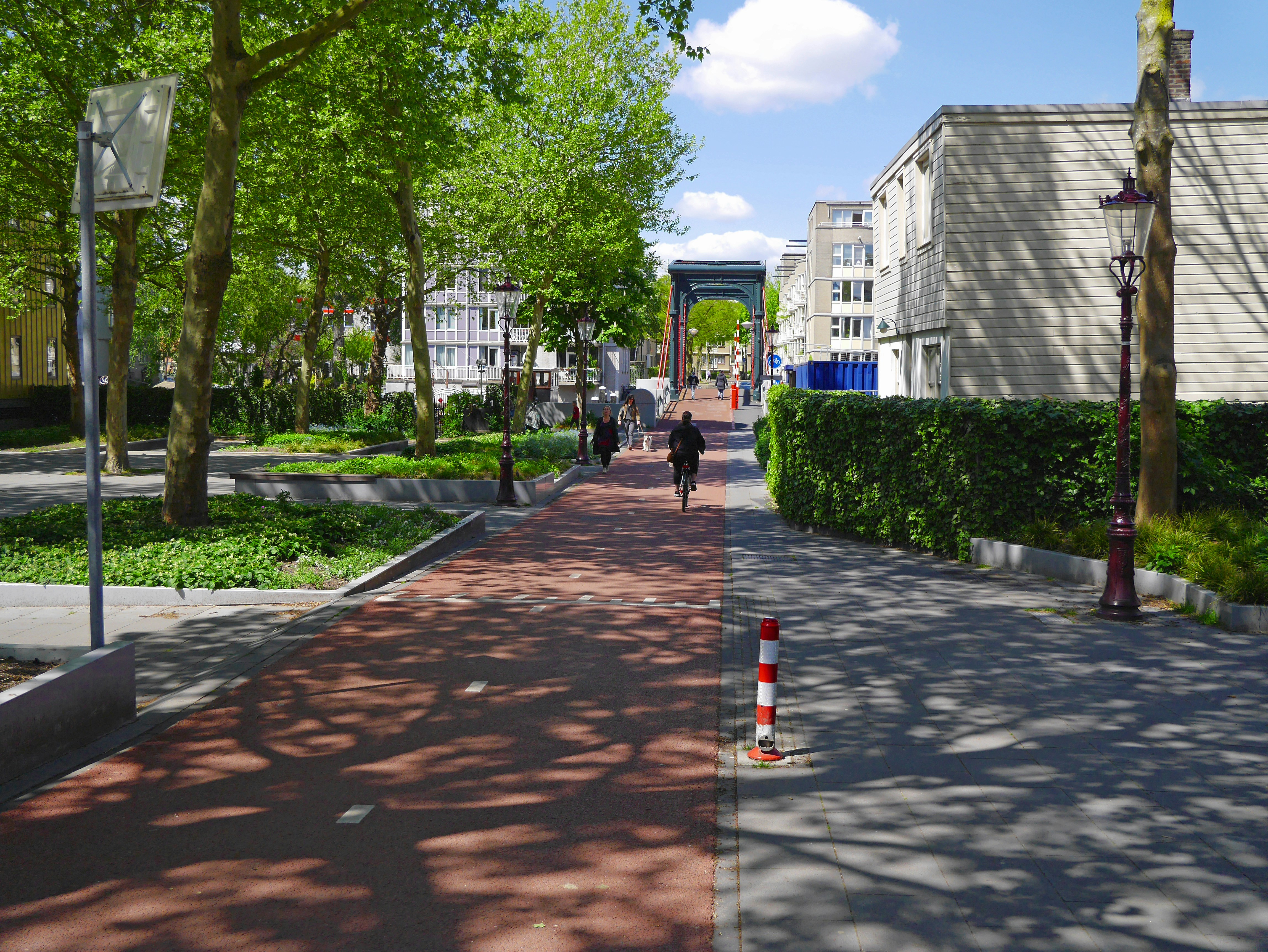 An illustrative photo of people walking on sidewalk near trees and building during daytime