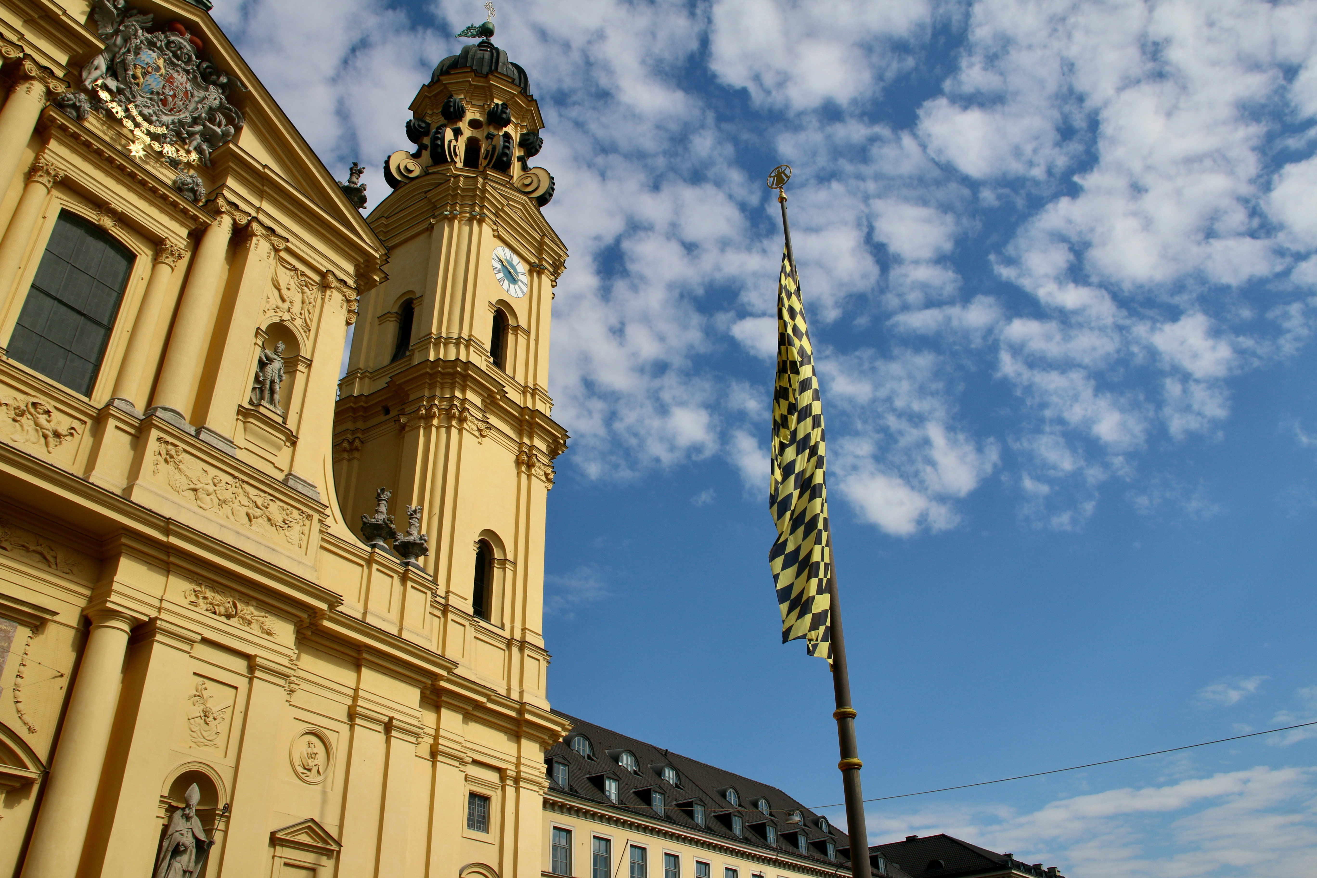 An illustrative photo of a large building with a clock tower and a flag in Munich, Germany