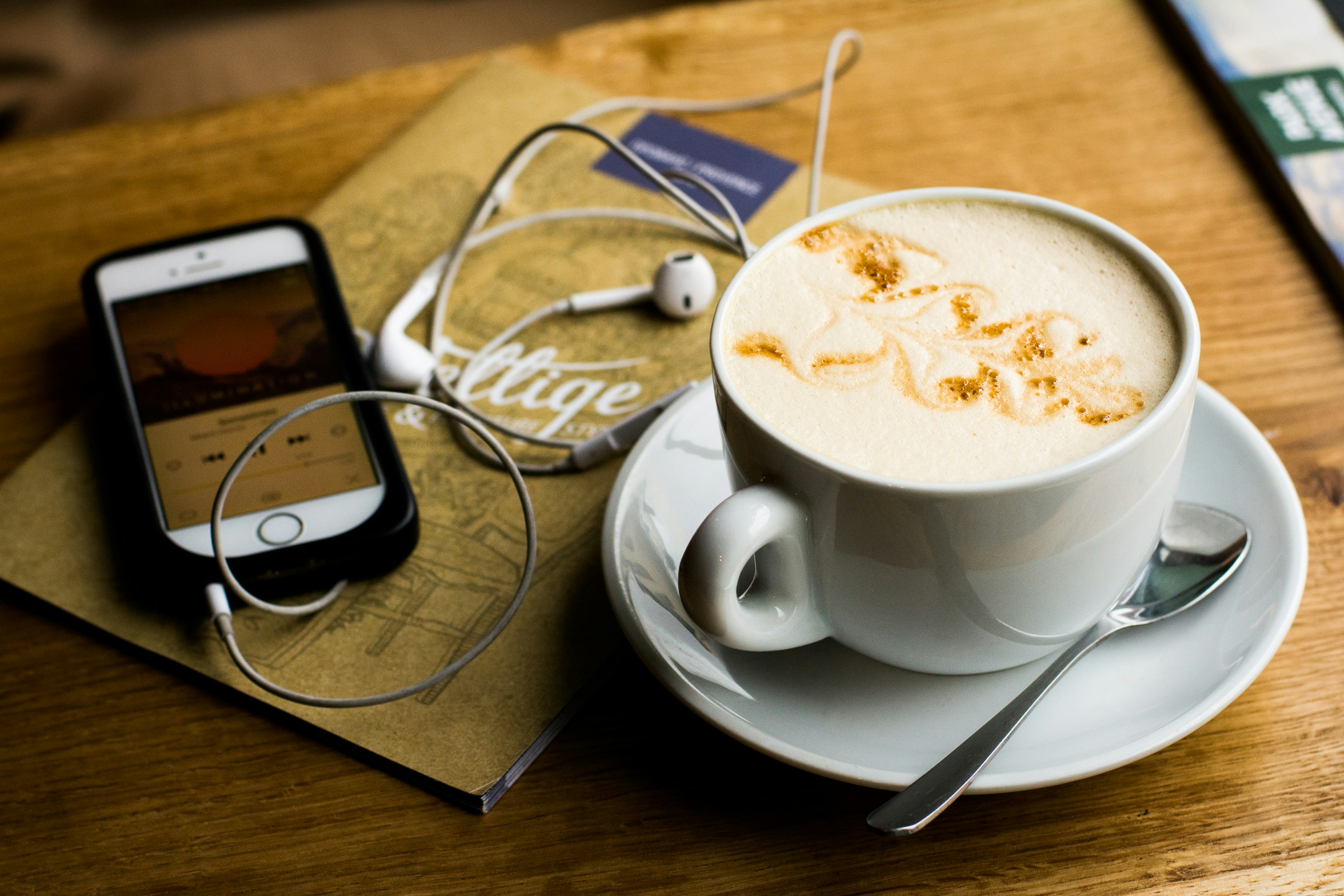 An illustrative photo of a coffee on a table near a phone and a notebook