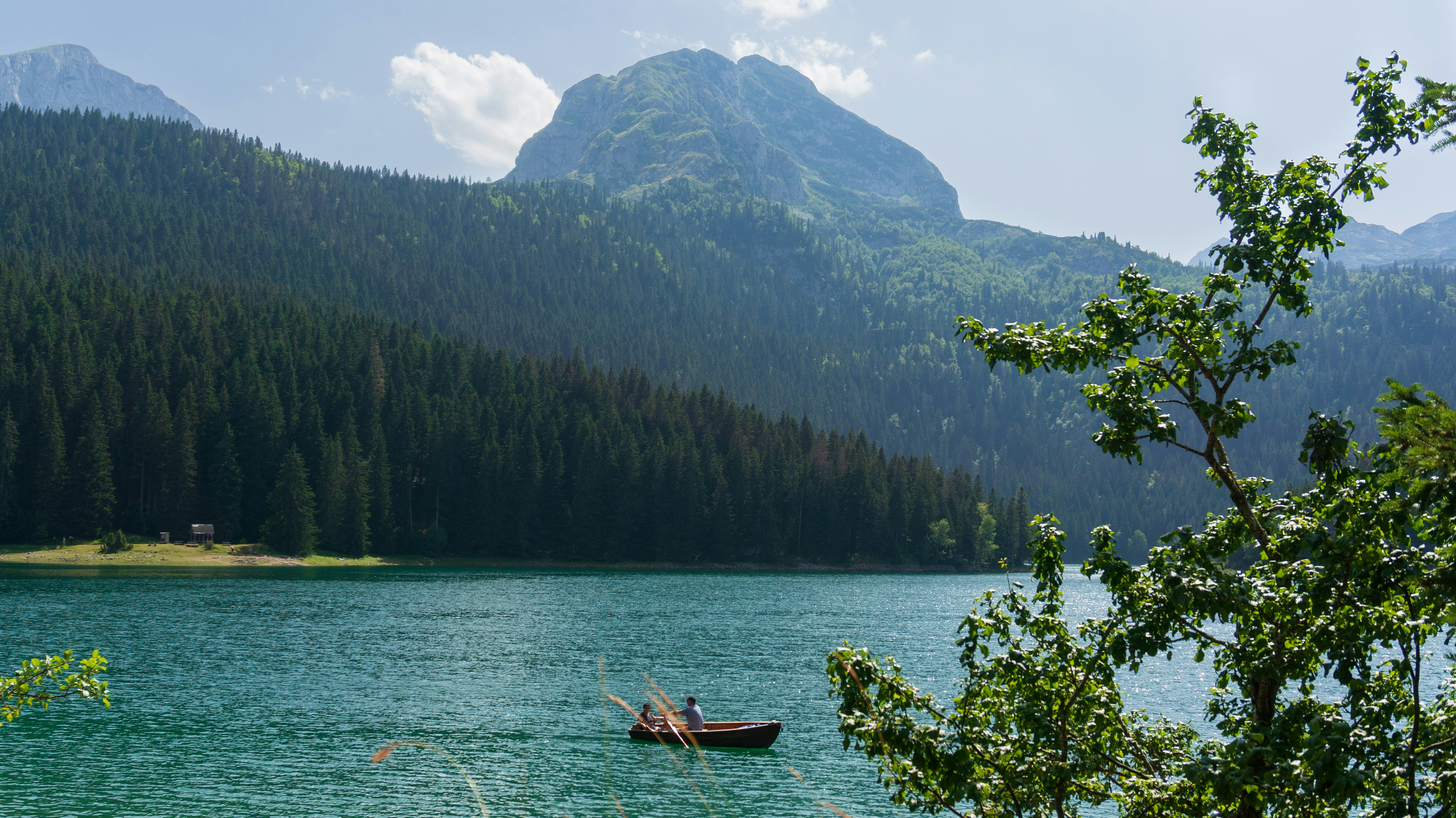 An illustrative photo of a boat floating on a lake with mountains in the background