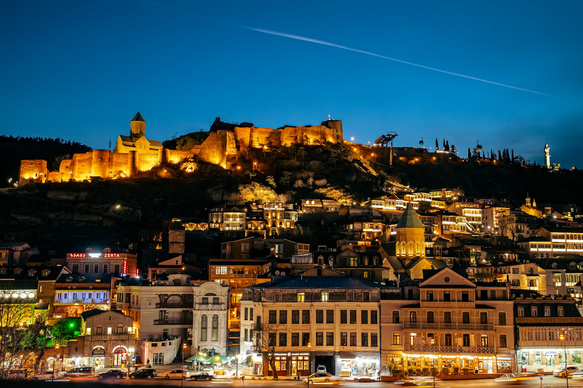 An illustrative photo of a night view of a city with a castle on a hill in the background