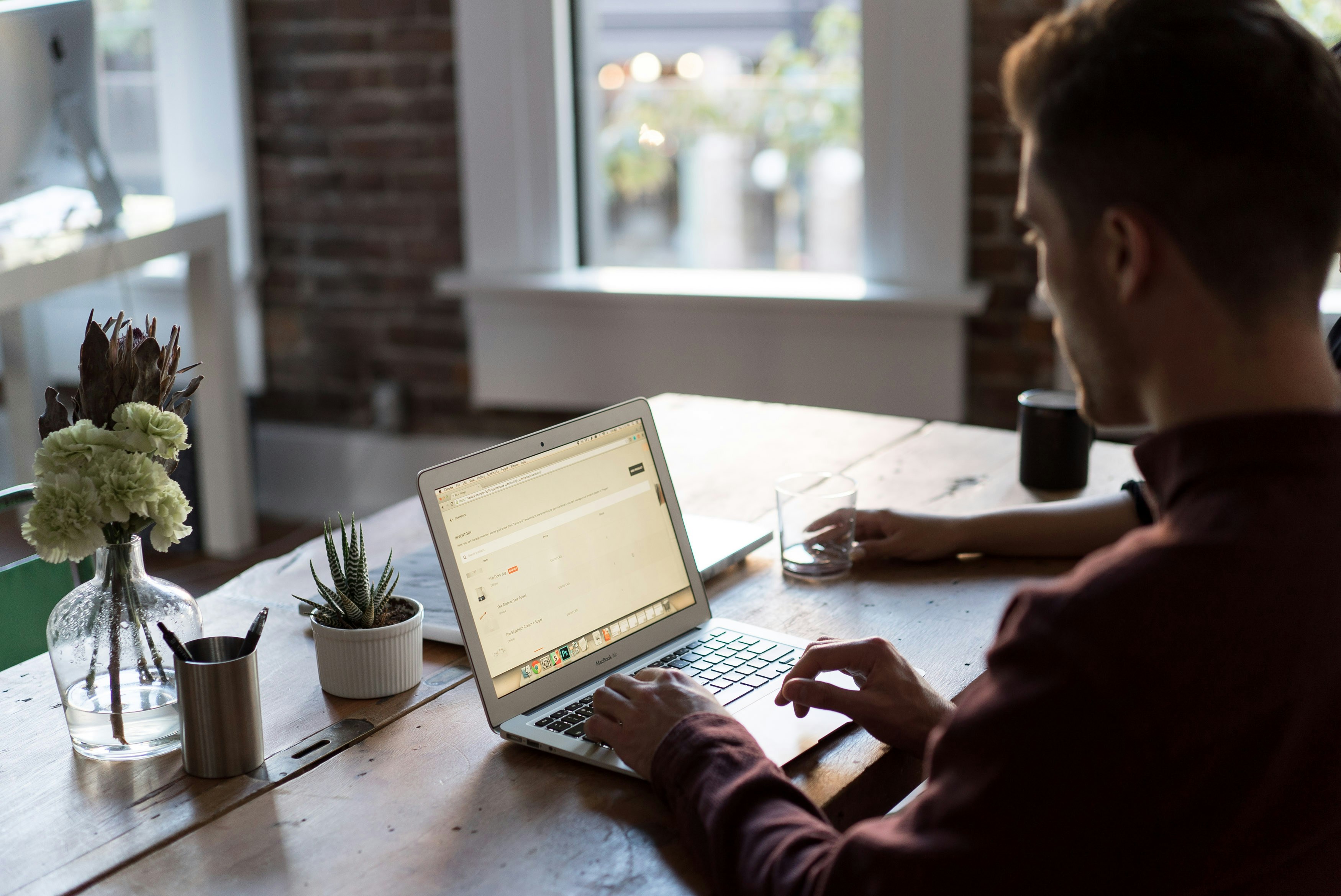 An illustrative photo of a man operating laptop on top of table