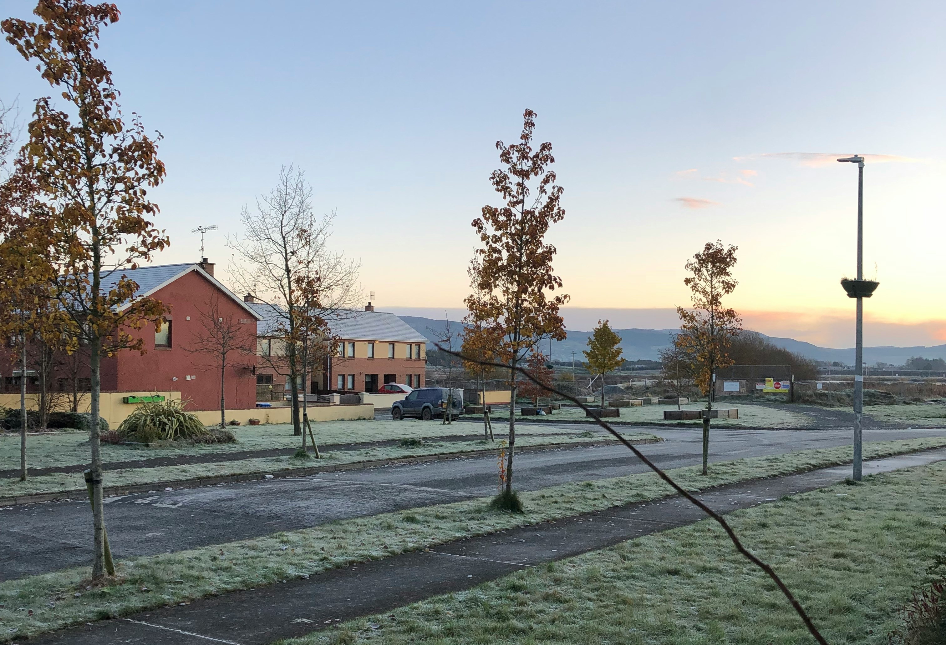 An illustrative photo of a grassy field with trees and buildings.