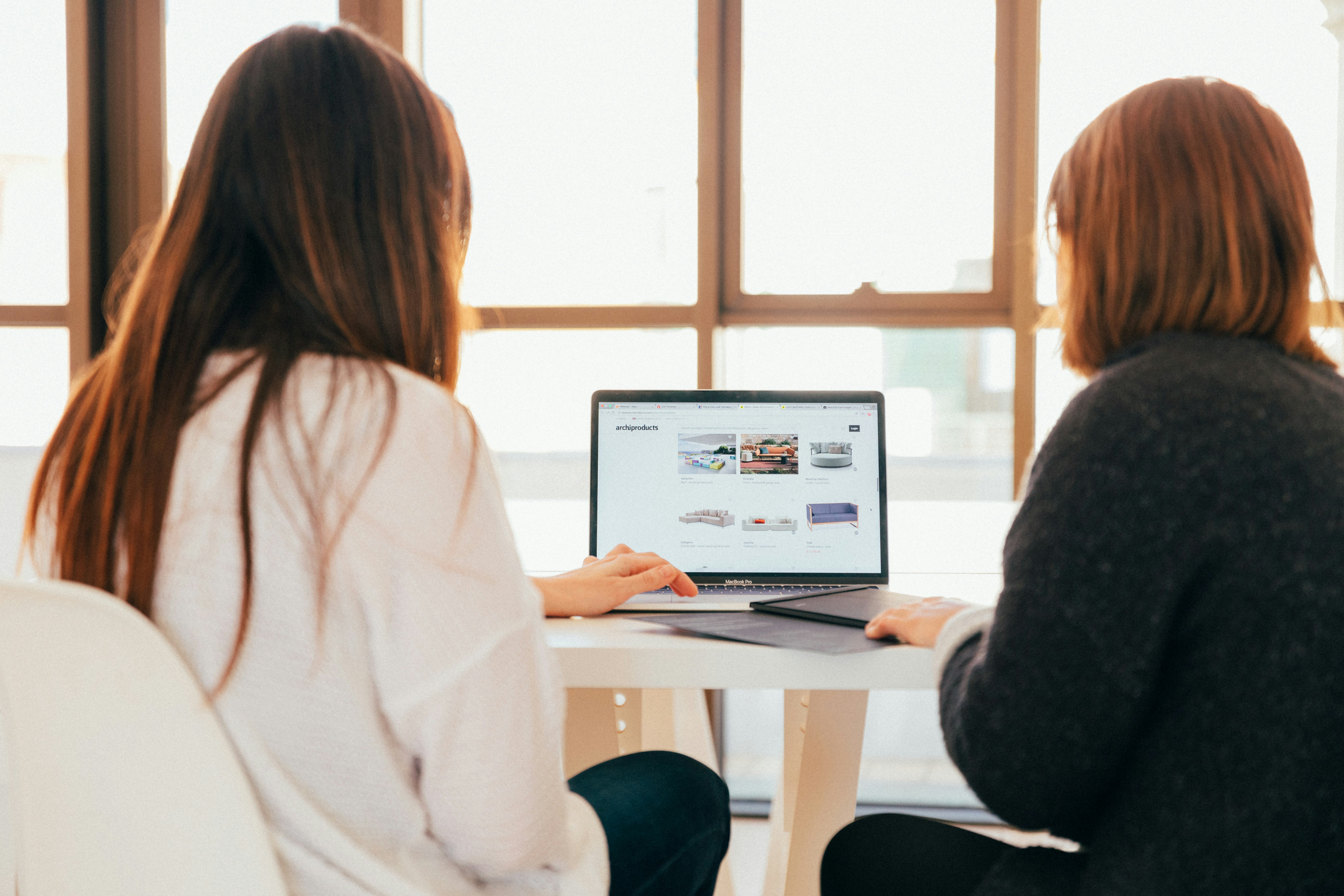 An illustrative photo of two women talking while looking at laptop computer