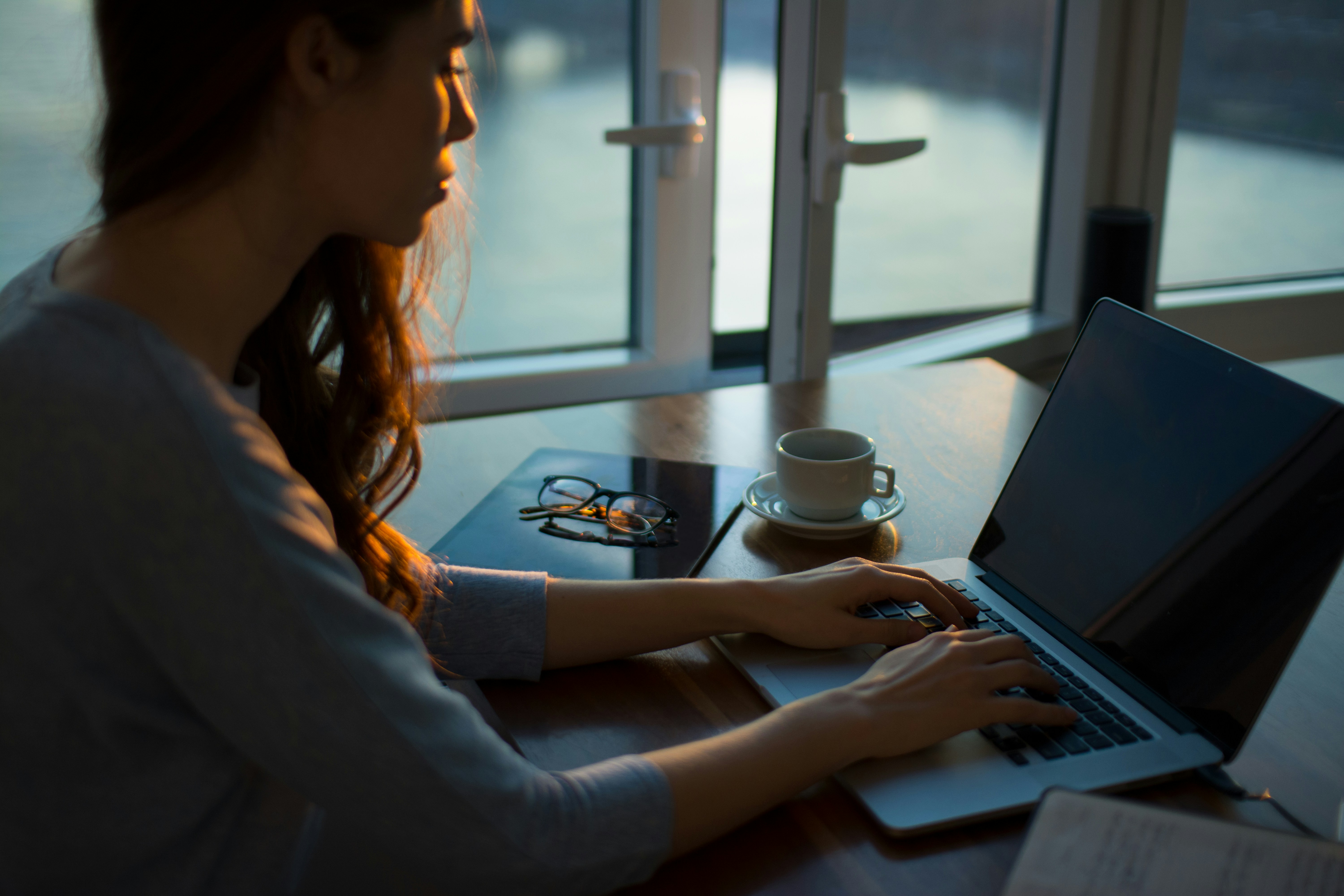 An illustrative photo of a woman sitting beside table using laptop