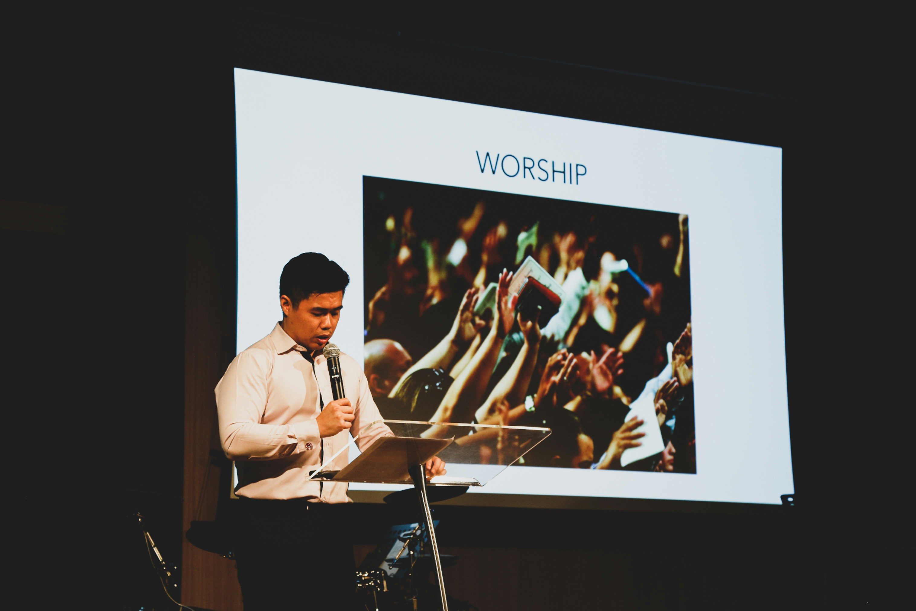 An illustrative photo of a man standing on stage and presenting 