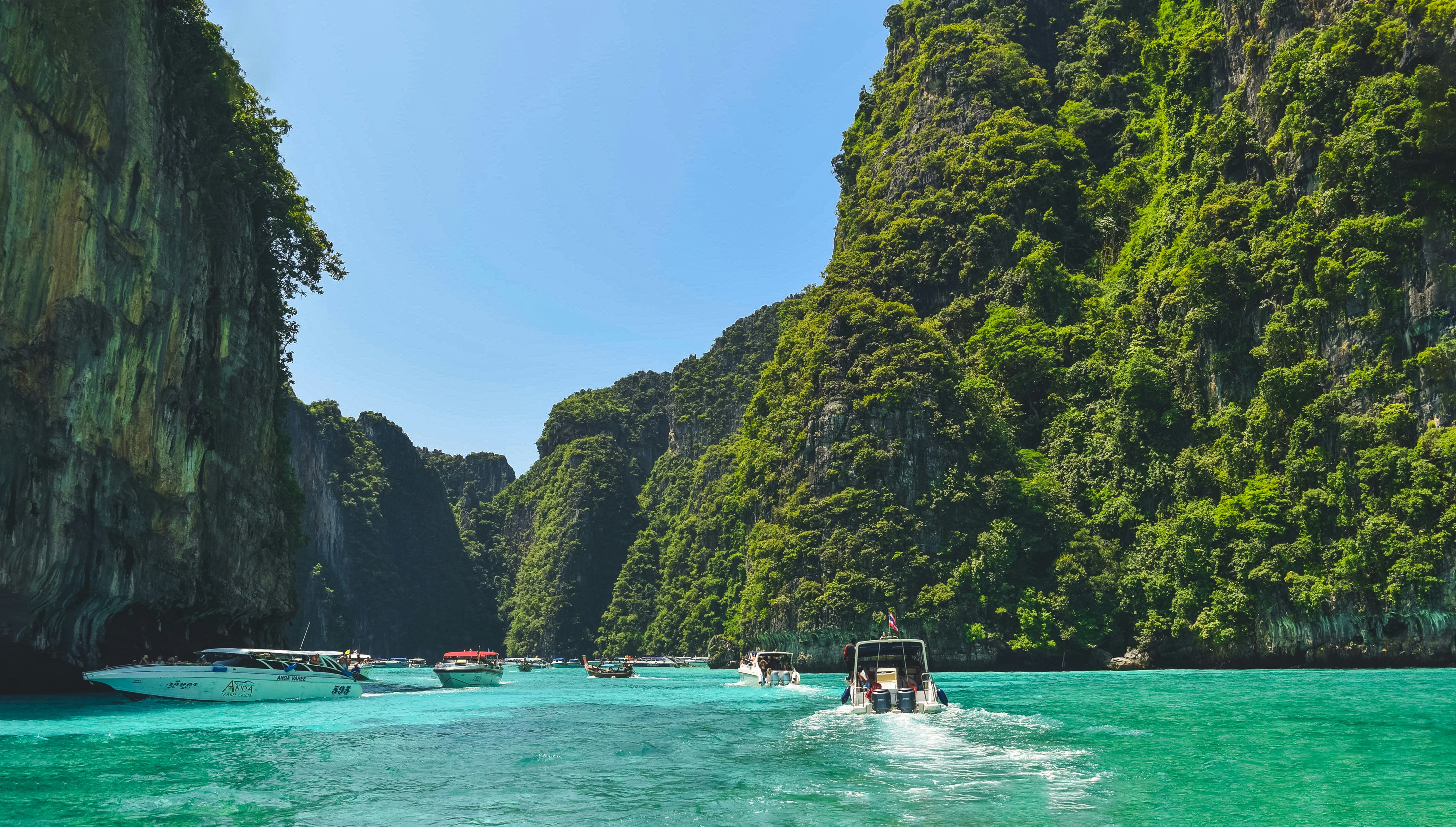 An illustrative photo of boats floating on top of a body of water near green hills