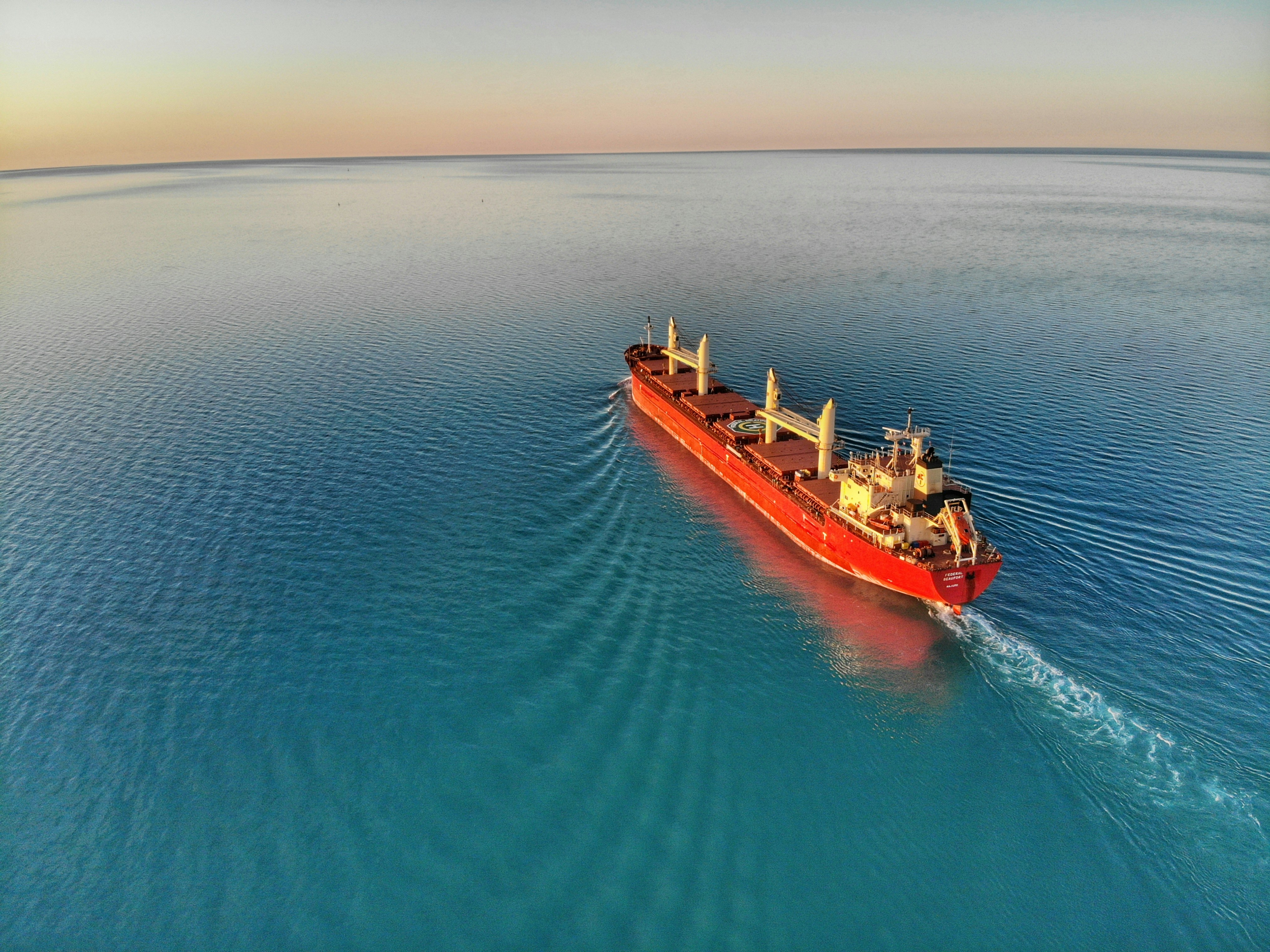 An illustrative photo of a red and white cargo ship at middle of ocean