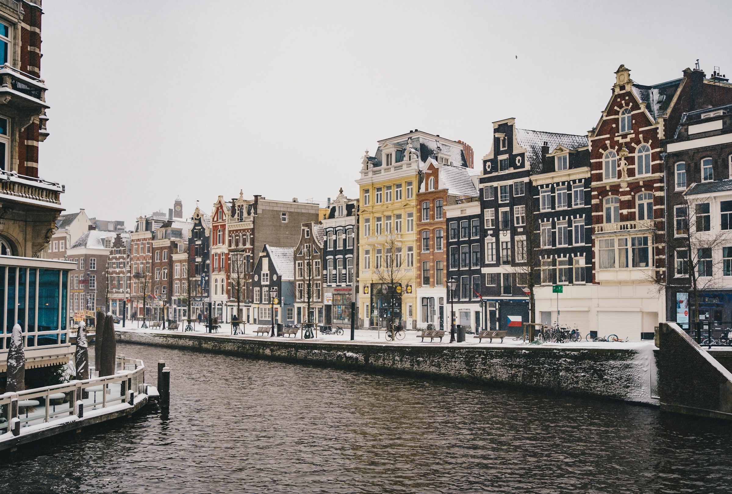 An illustrative photo of buildings covered with snow near a body of water