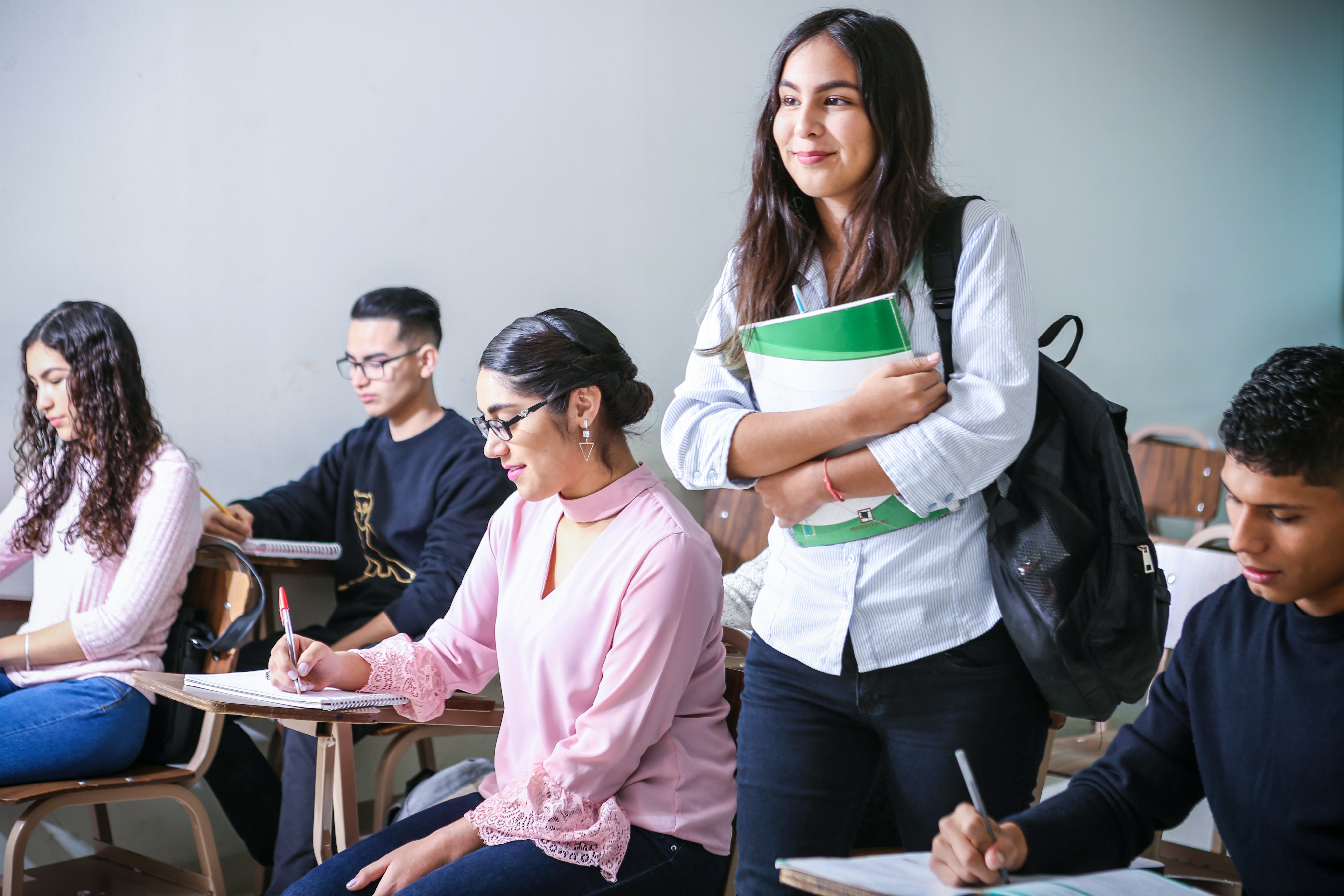 An illustrative photo of a student carrying a textbook in the class