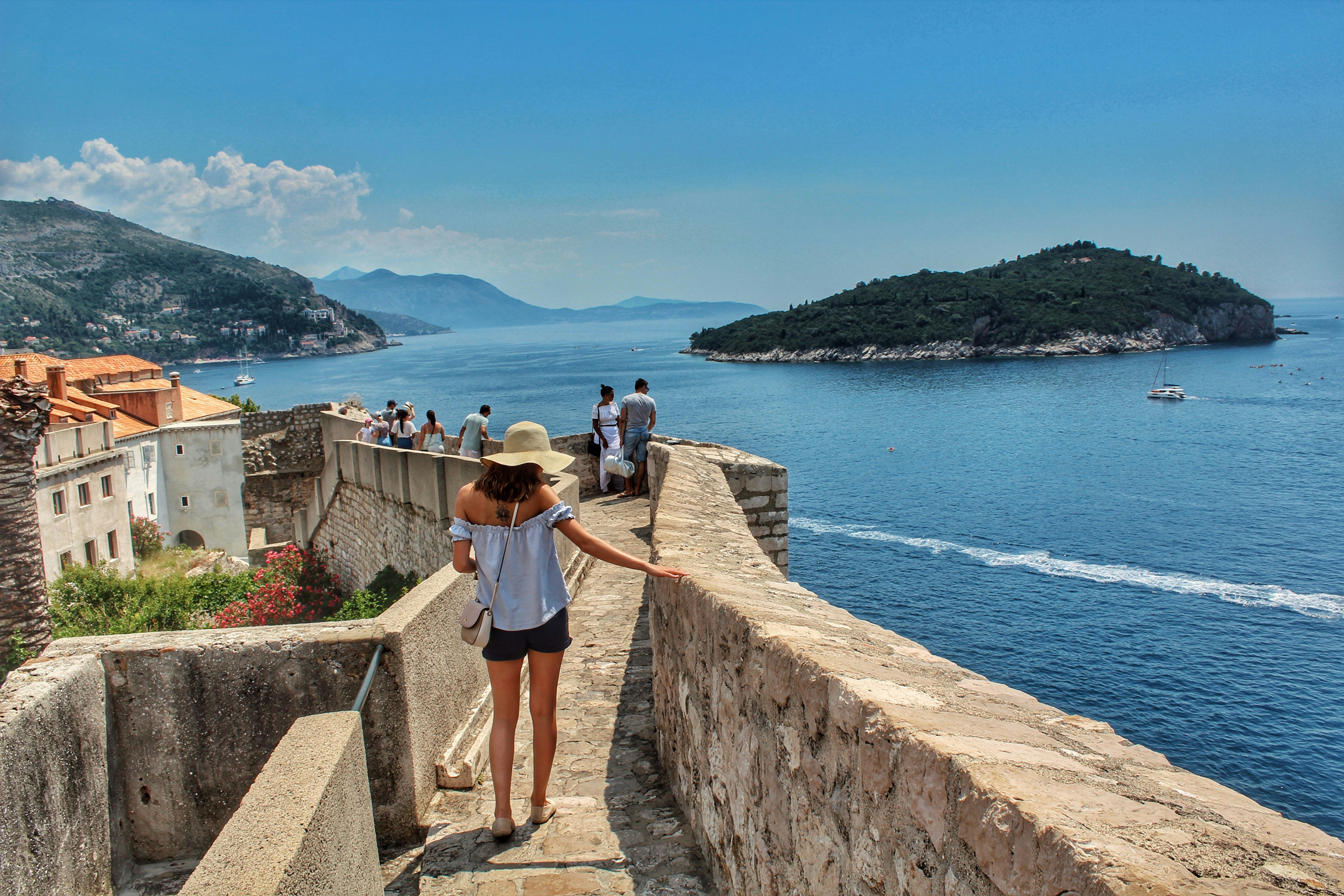 An illustrative photo of people walking on concrete pathway near a body of water