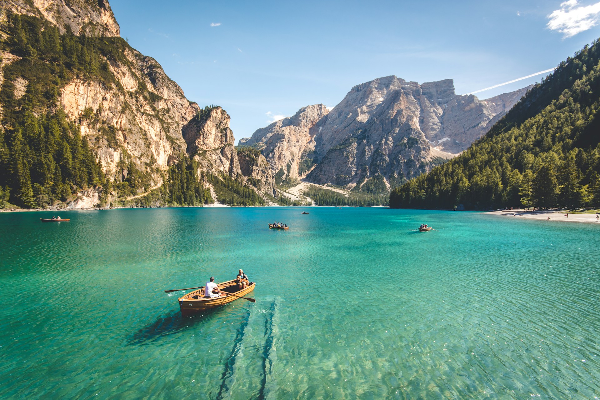 An illustrative photo of wooden boats on a blue lake between mountains