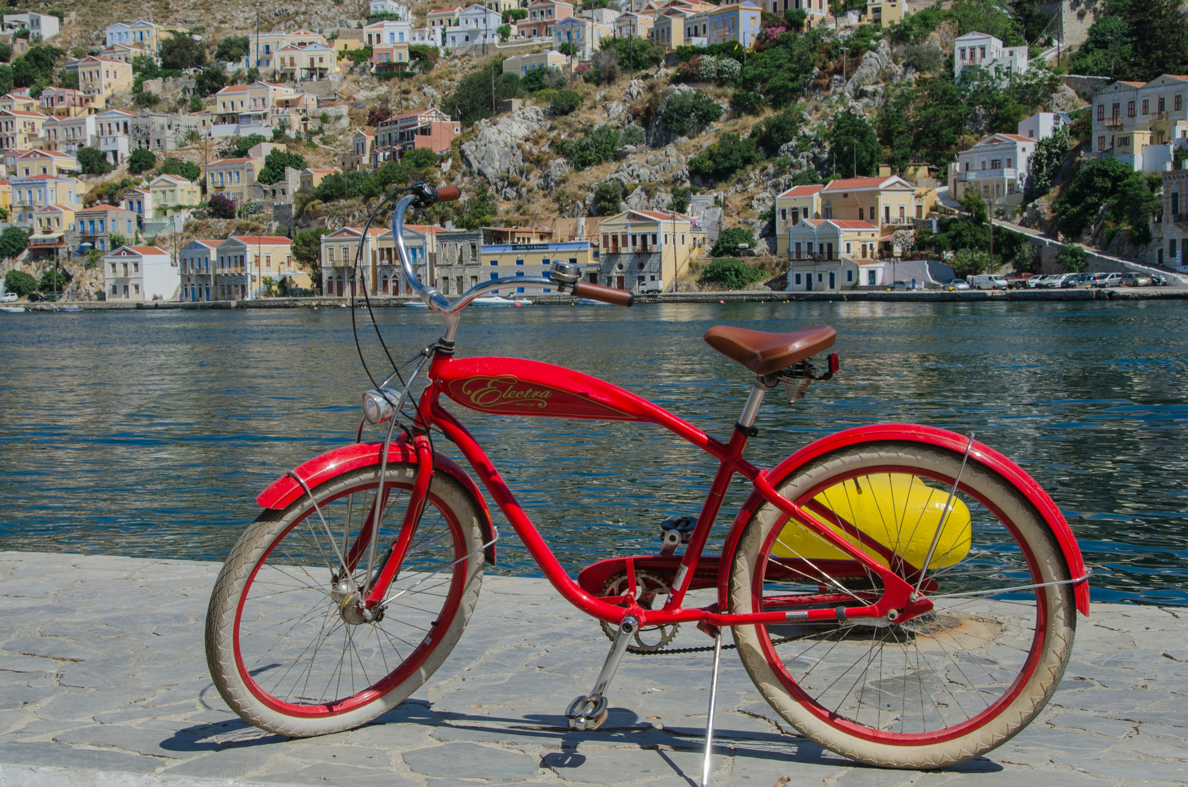 Photo by Unsplash An illustrative photo of a red bicycle near a body of water with a city in the background