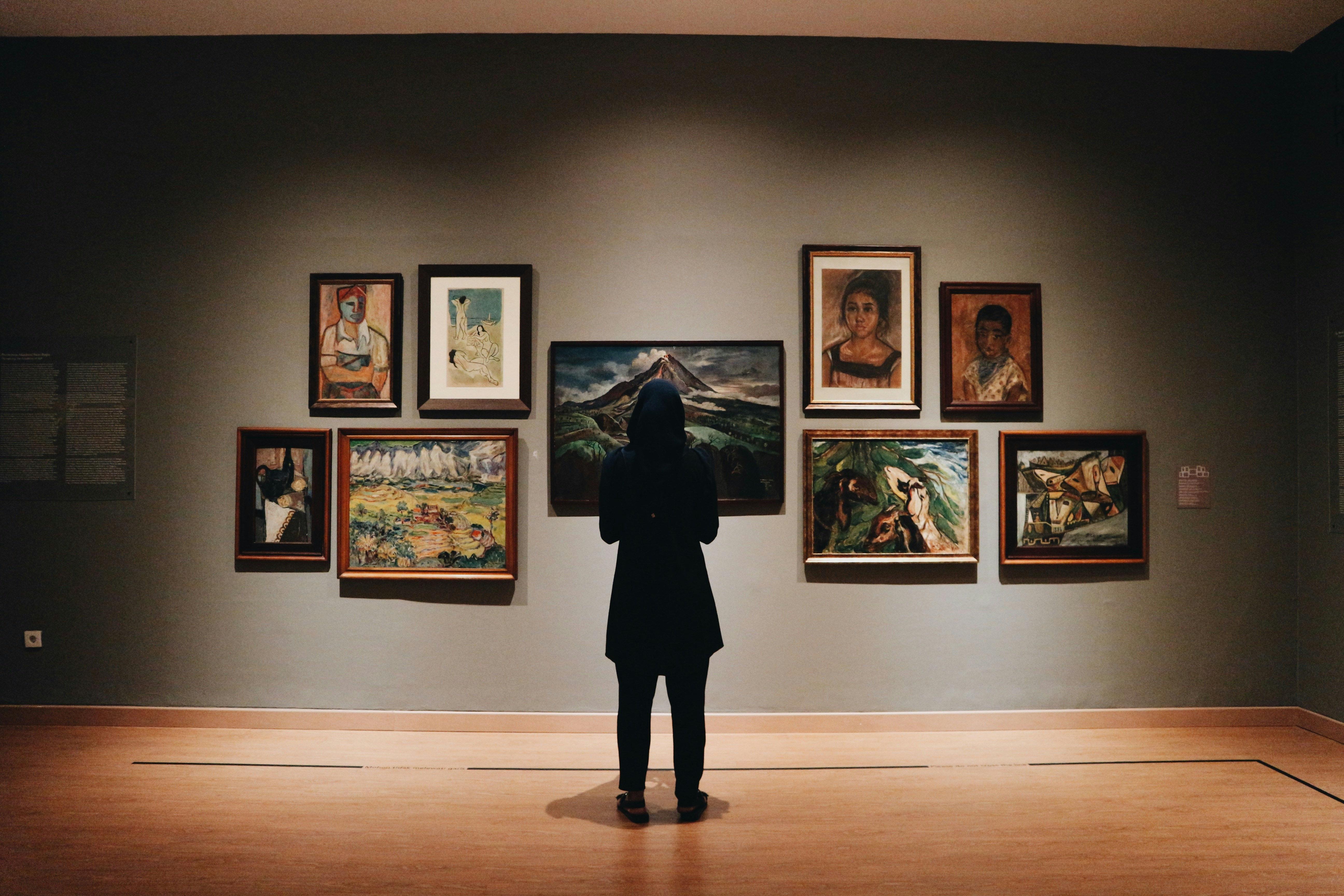 An illustrative photo of a woman standing in front of paintings