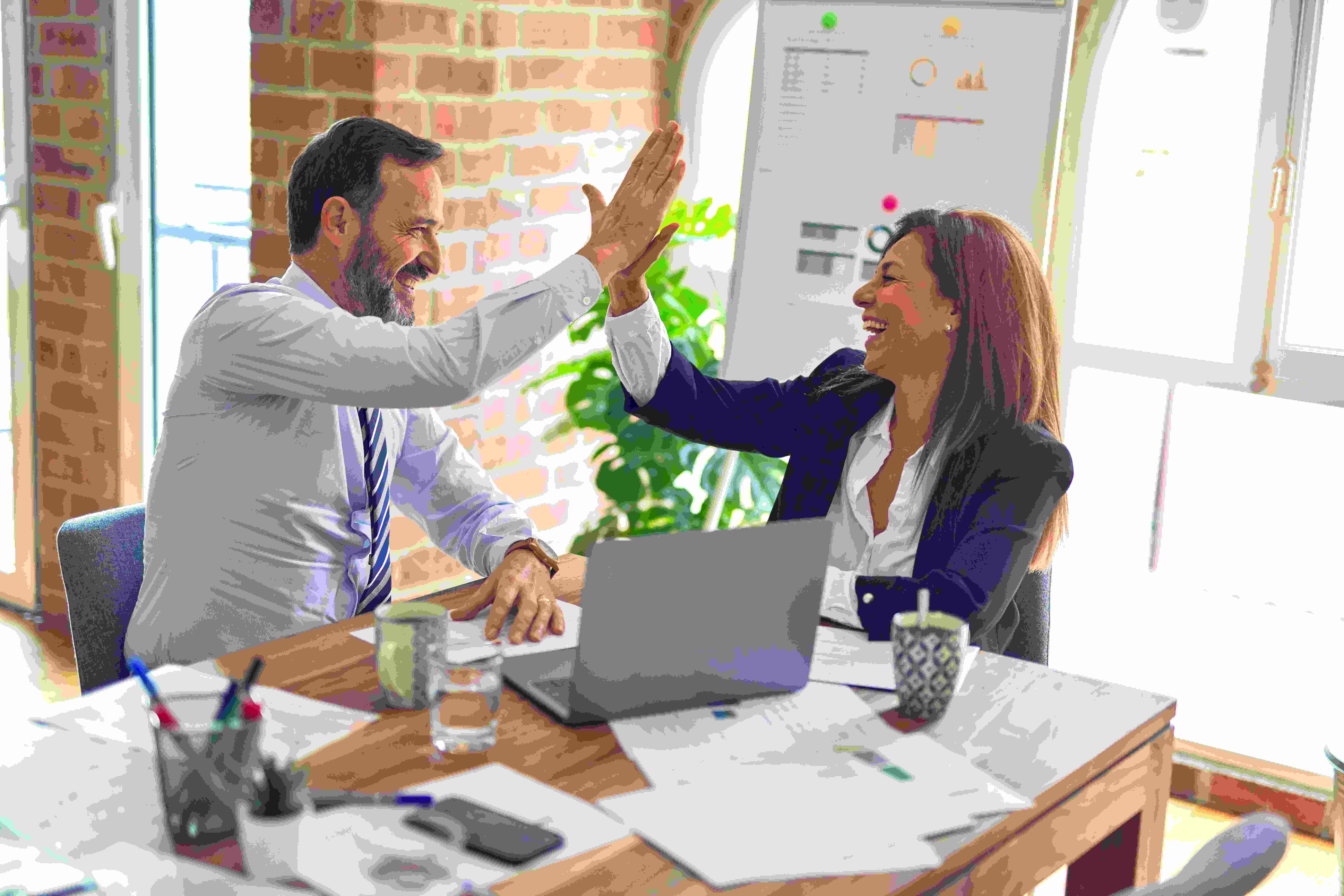 An illustrative photo of two business workers smiling while working.