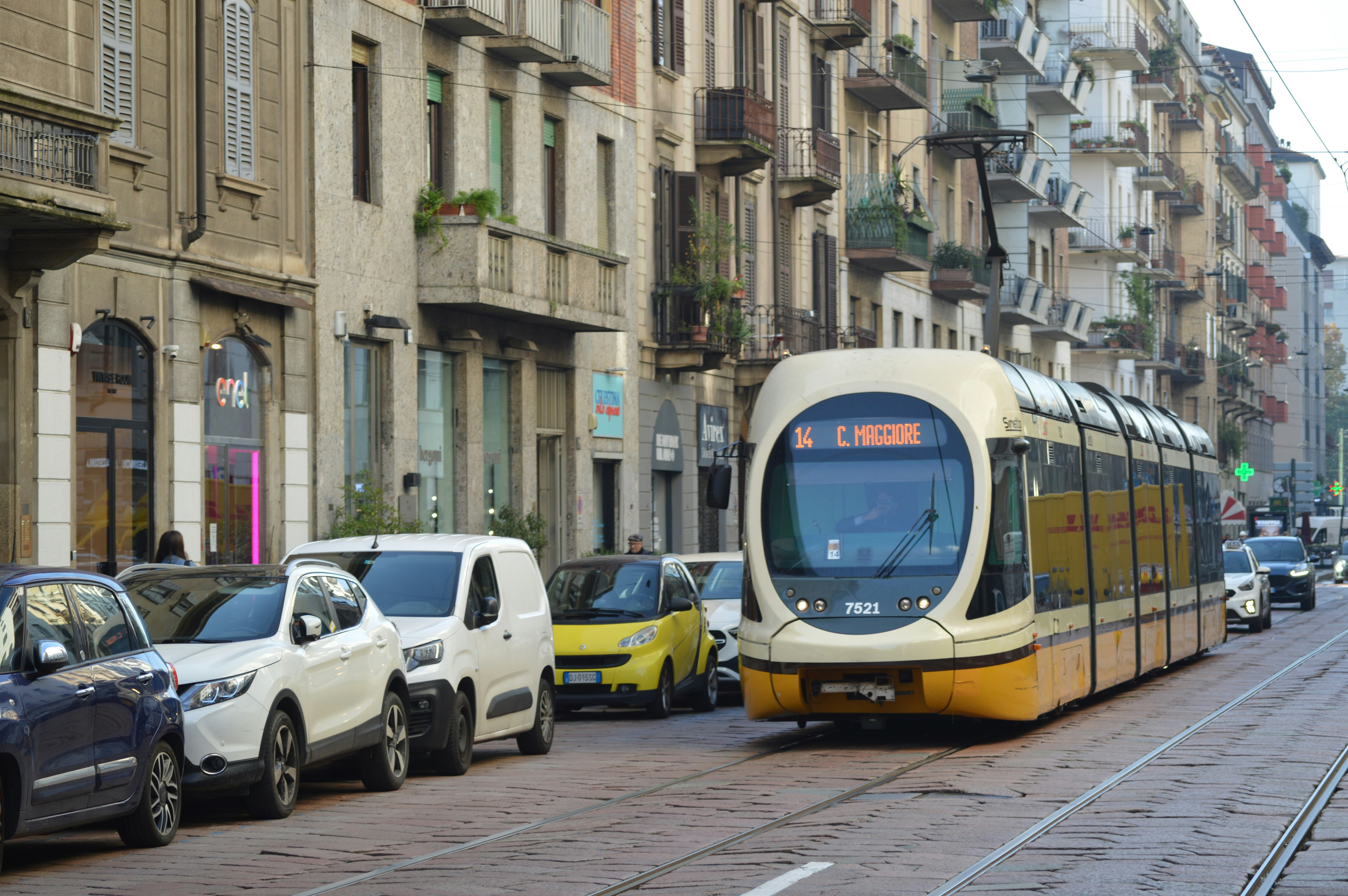 An illustrative photo of a tram and cars on a road in a city.