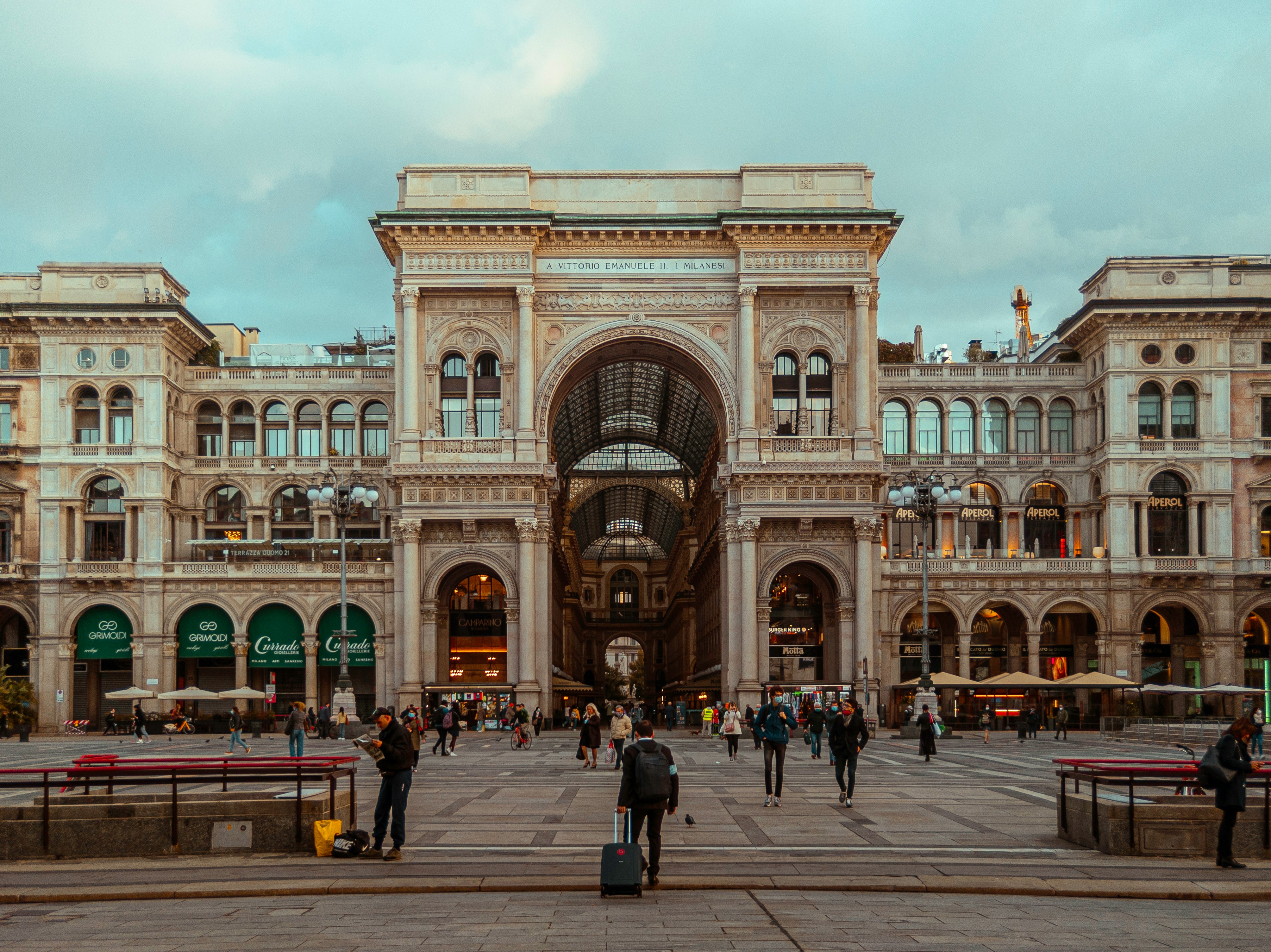 Image by Unsplash An illustrative photo of people walking near a big beige building with an arch.