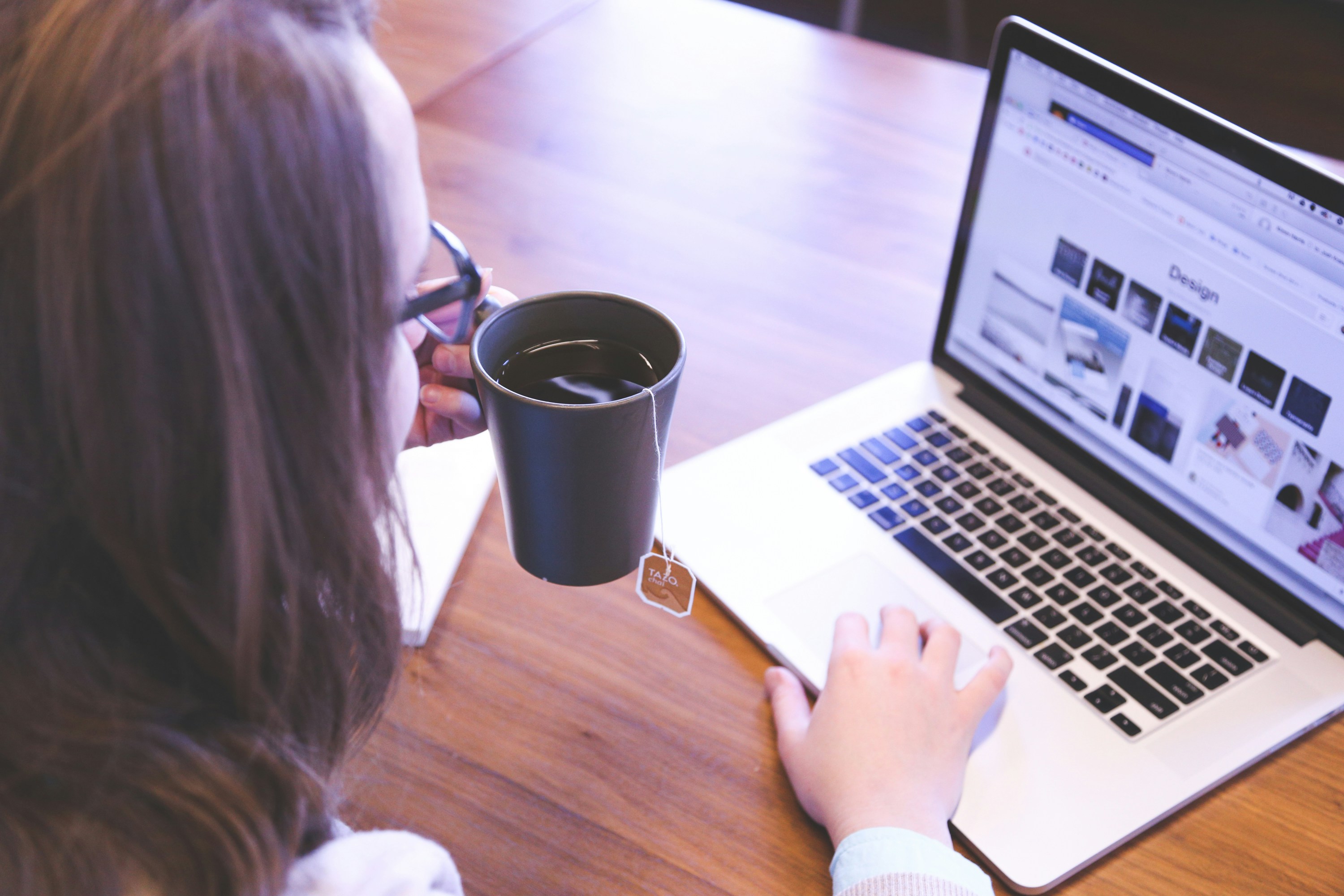 An illustrative photo of a woman working on a laptop while drinking tea.