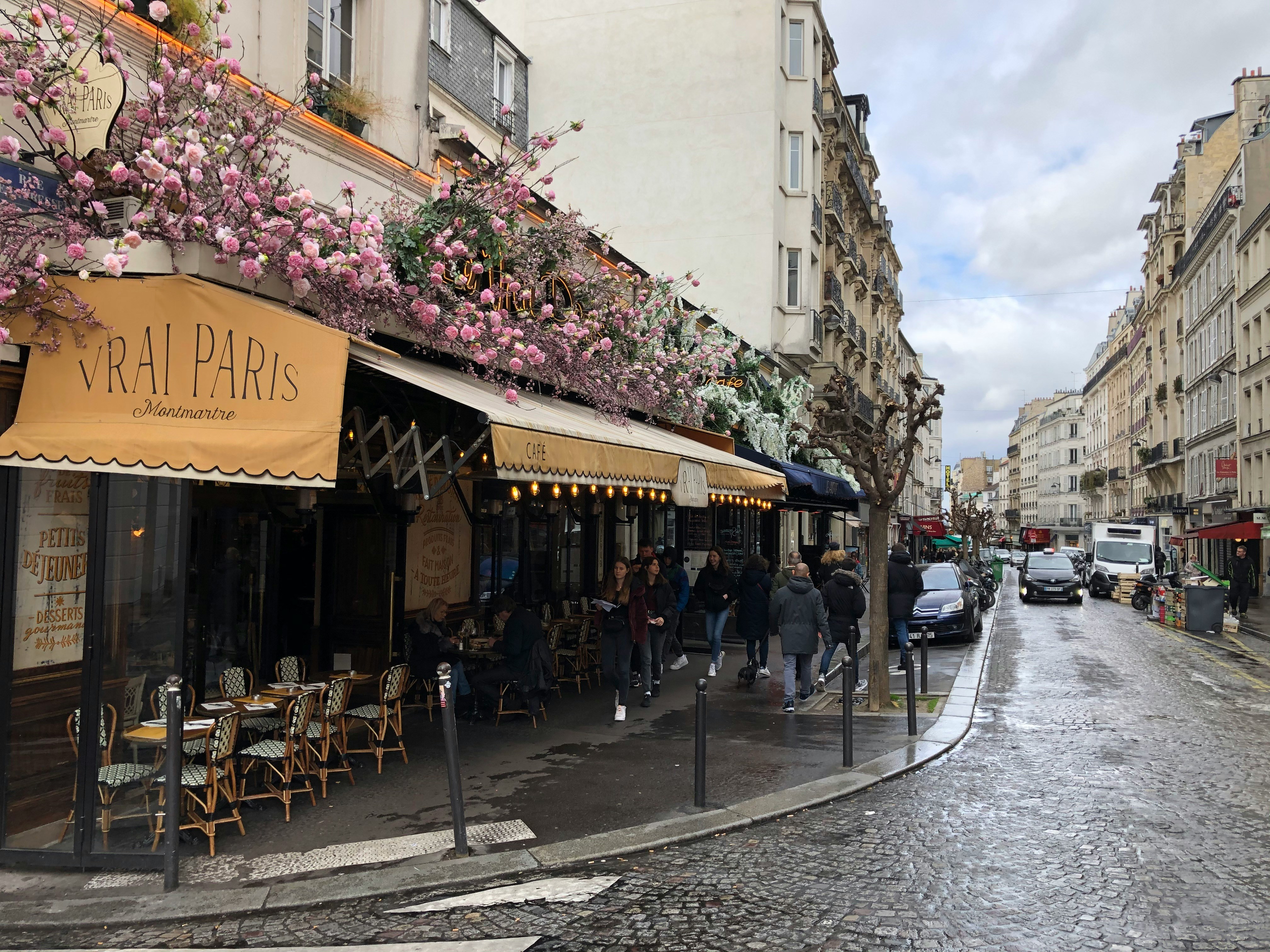 Image by Unsplash An illustrative photo of a café on a Paris street with pink flowers.
